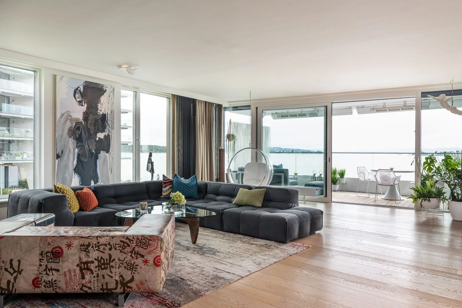 Stue med stor sofa, kunst og utsikt mot fjorden, leilighet på Tjuvholmen