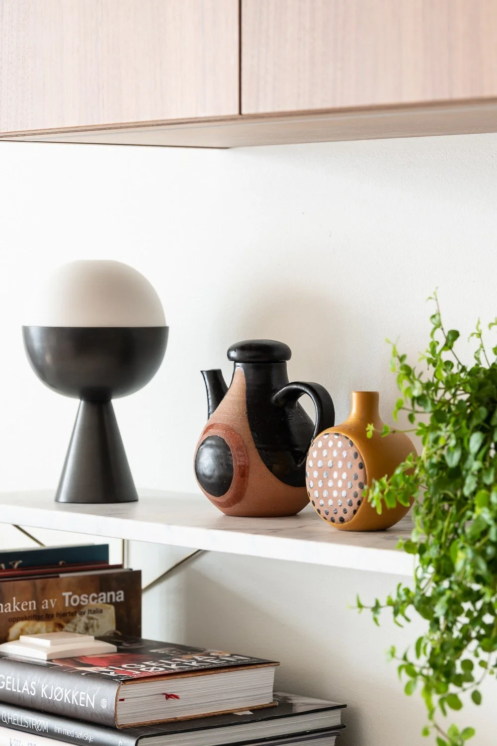 Detalj fra kjøkkenhylle med lampe og keramikk, leilighet på Tjuvholmen