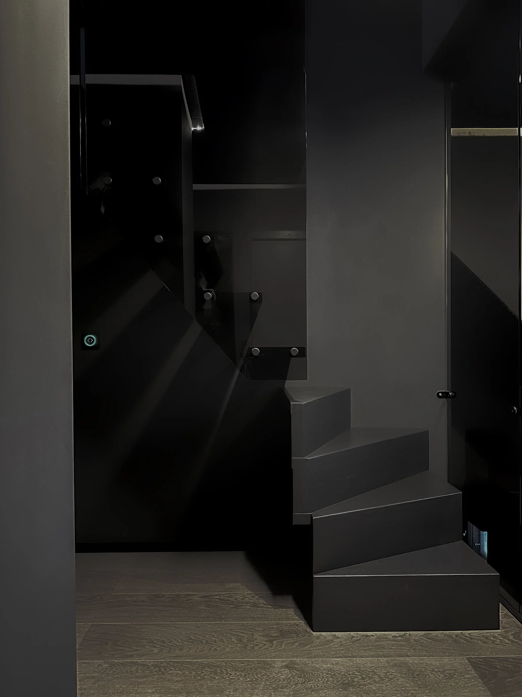 Interior of a modern elevator with black walls, stepping-stone design floor, and closed doors.