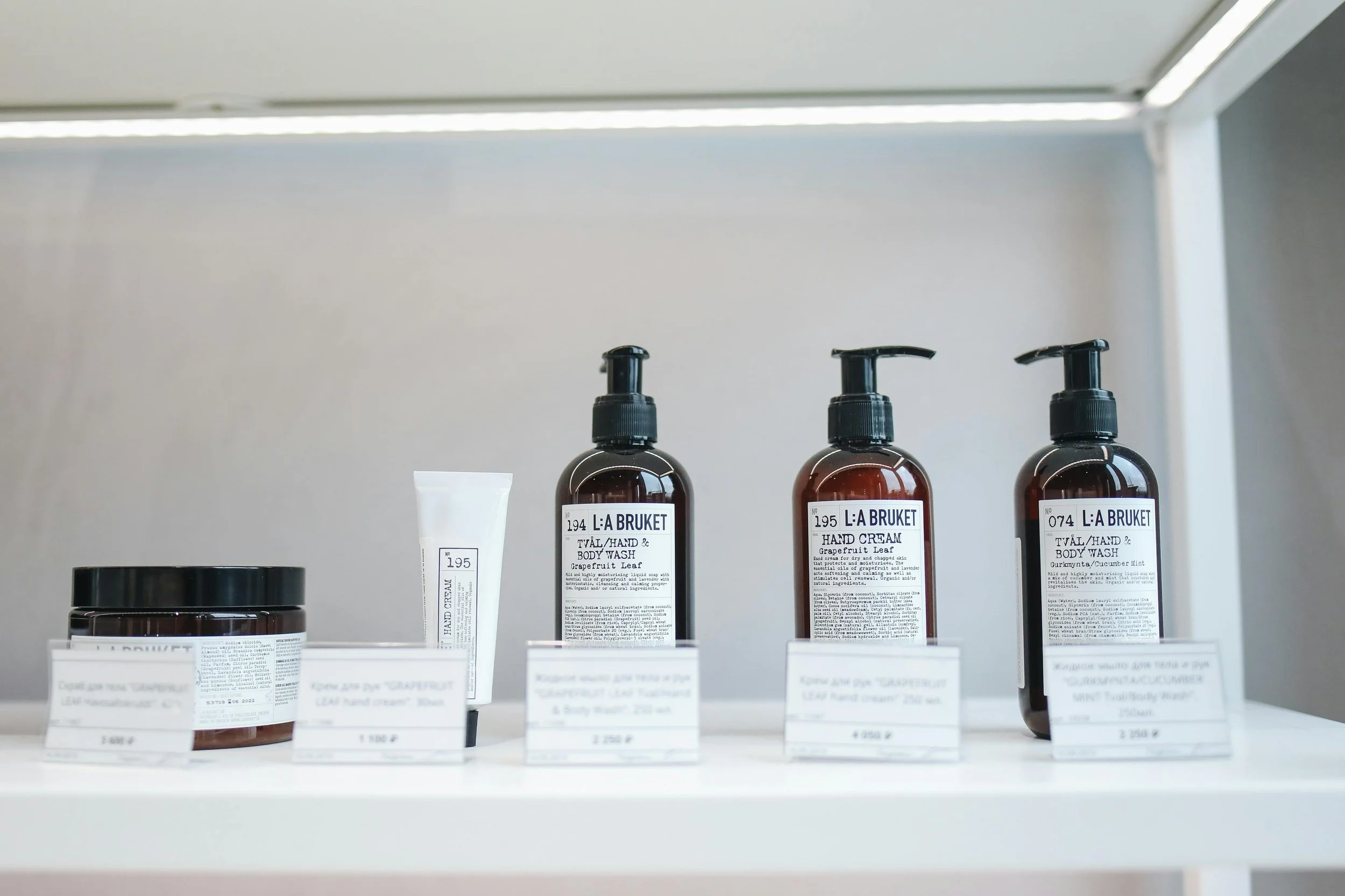 Display of skincare products on a white shelf, including jars and bottles labeled with brand 'L:A BRUKET'.
