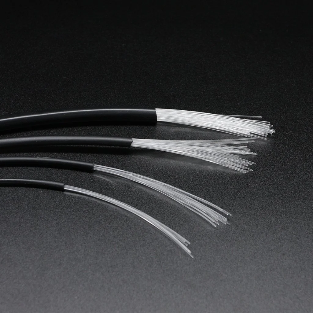 Tre optiske fiberkabler med sorte ytre omgivelser og tynne, gjennomsiktige indre fibre på en svart overflate.