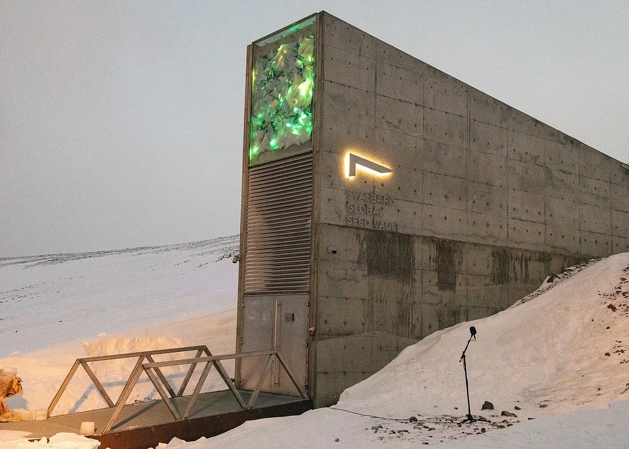 Modern betongbygning med lysende kutt i veggen, omgitt av snø, med utømmelig lys i en grønn nyanse, i kaldt vær.