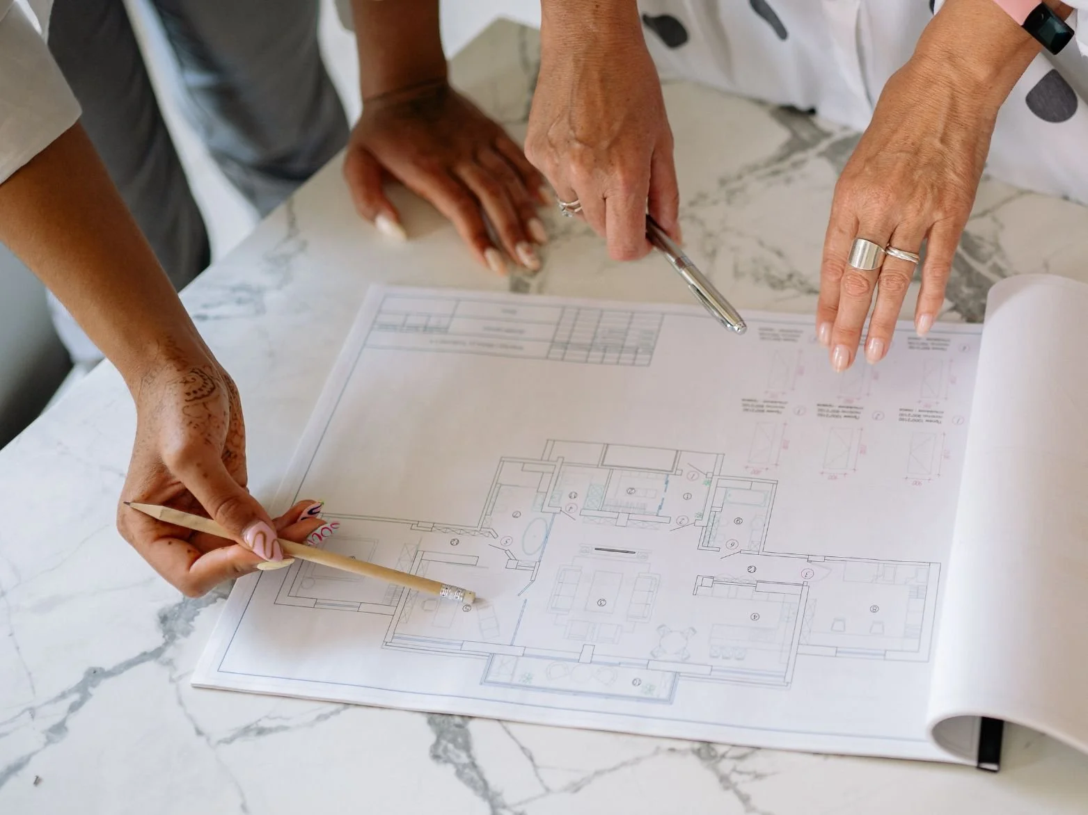 To personer peker på en arkitekturplan eller tegning på et bord.