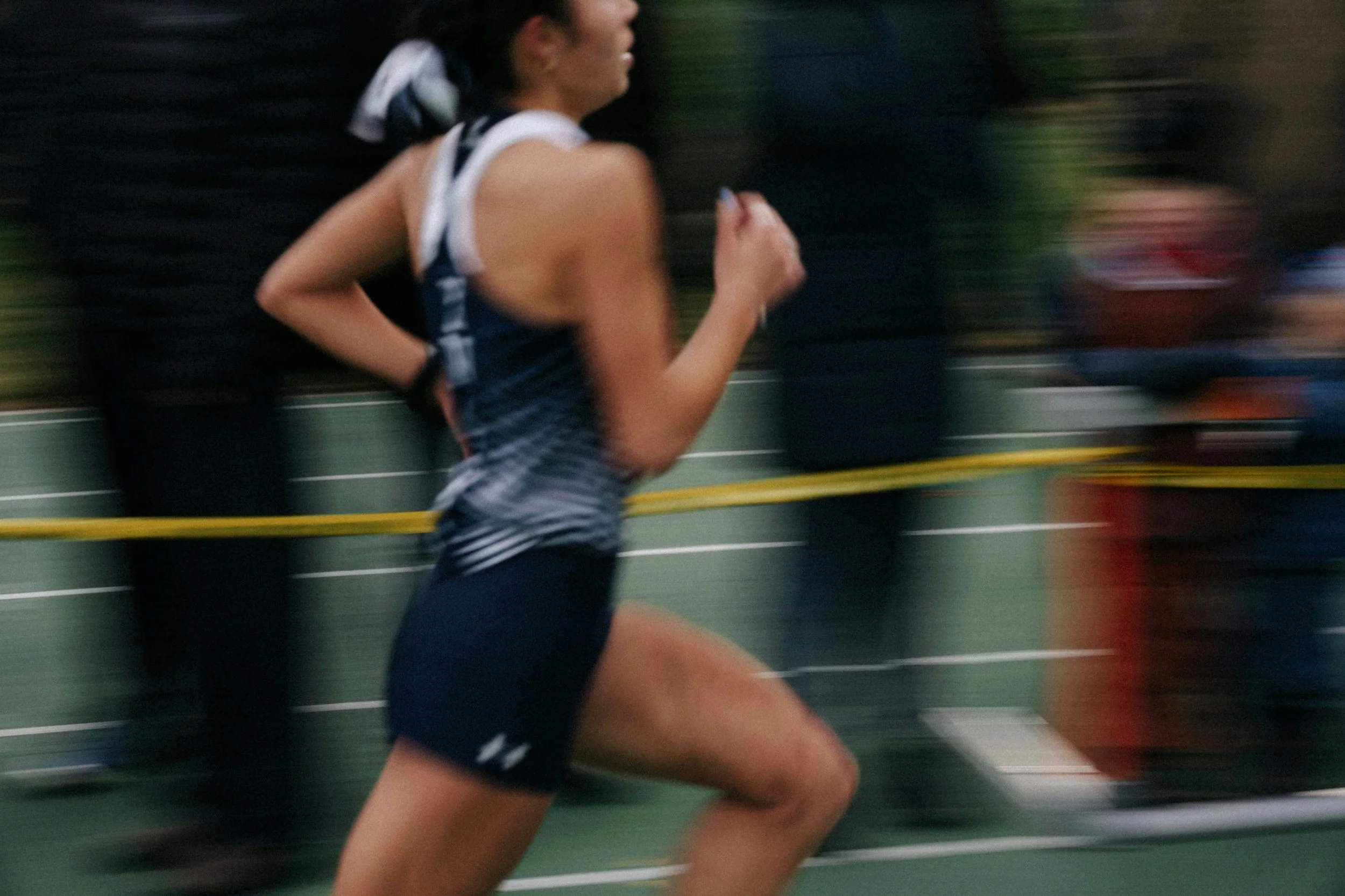 A female runner wearing a black and white sports outfit running on a track.