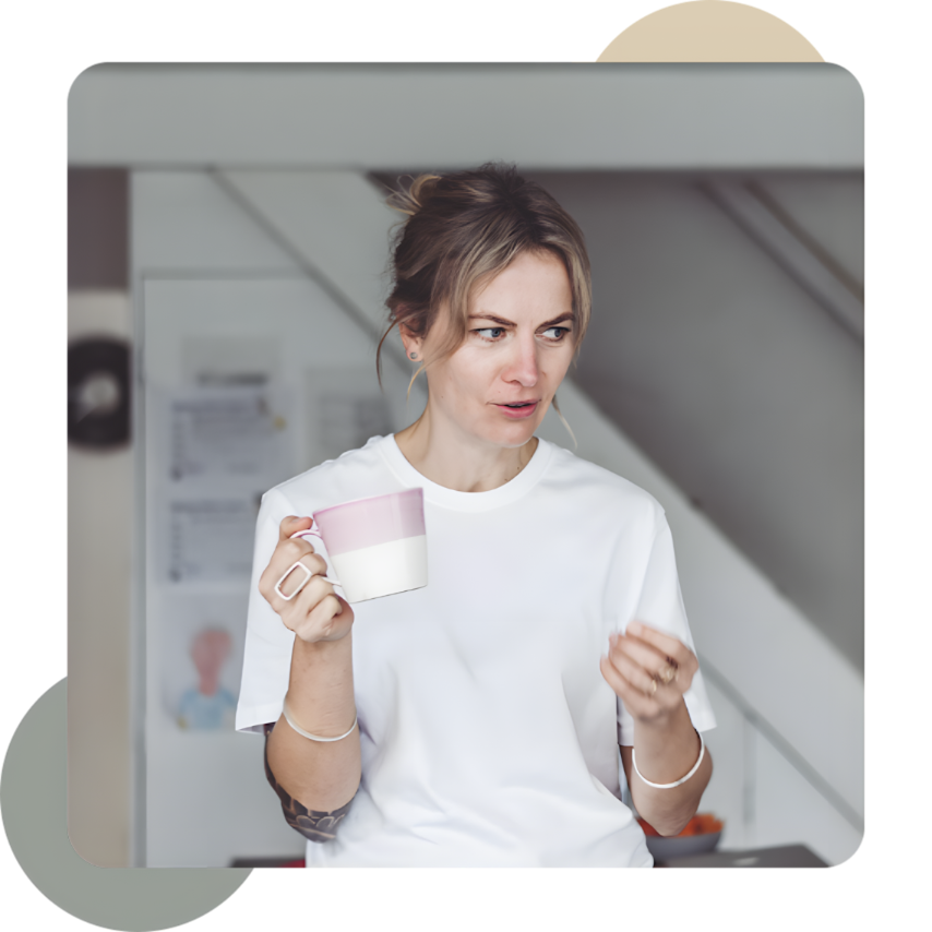 A woman holding a coffee mug with a confused or skeptical expression on her face in a kitchen.