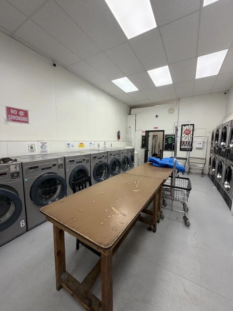 Laundry room with washing machines, a wooden table, shopping cart, and a