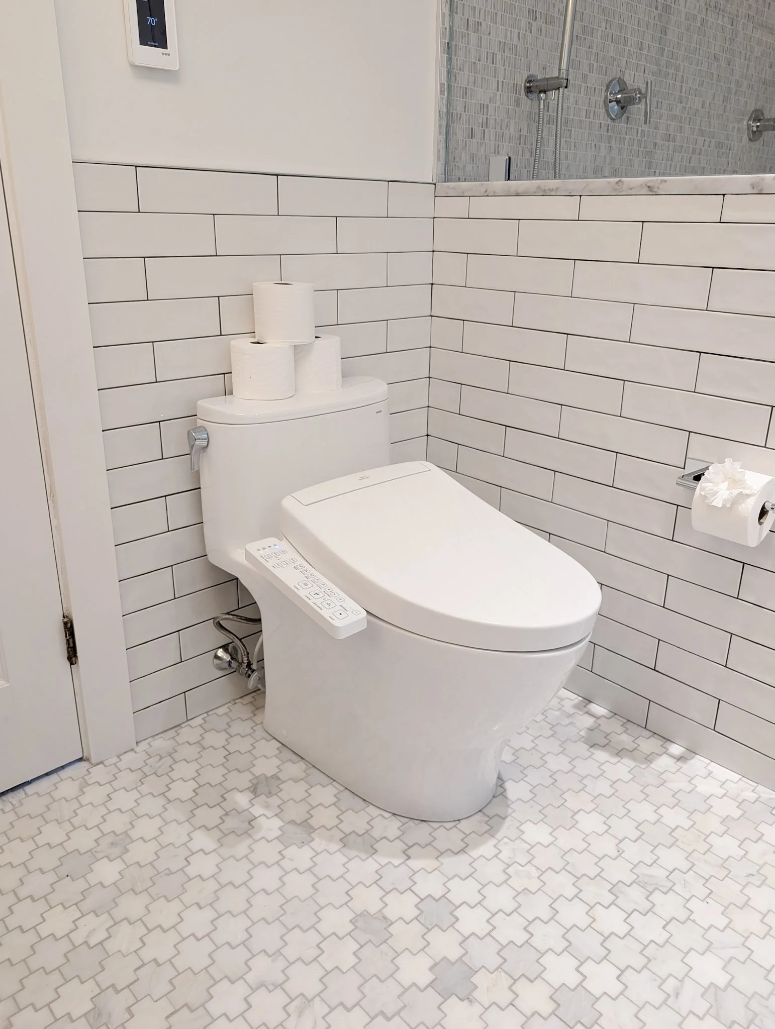 toilet with a stack of toilet paper on the back