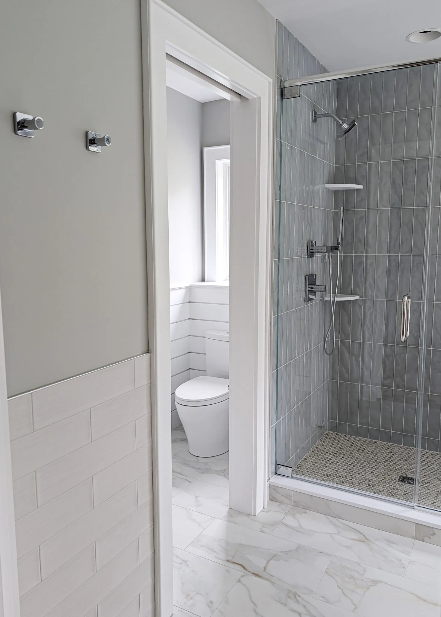 View of a modern bathroom showing a glass door shower, toilet, and different tile finishes