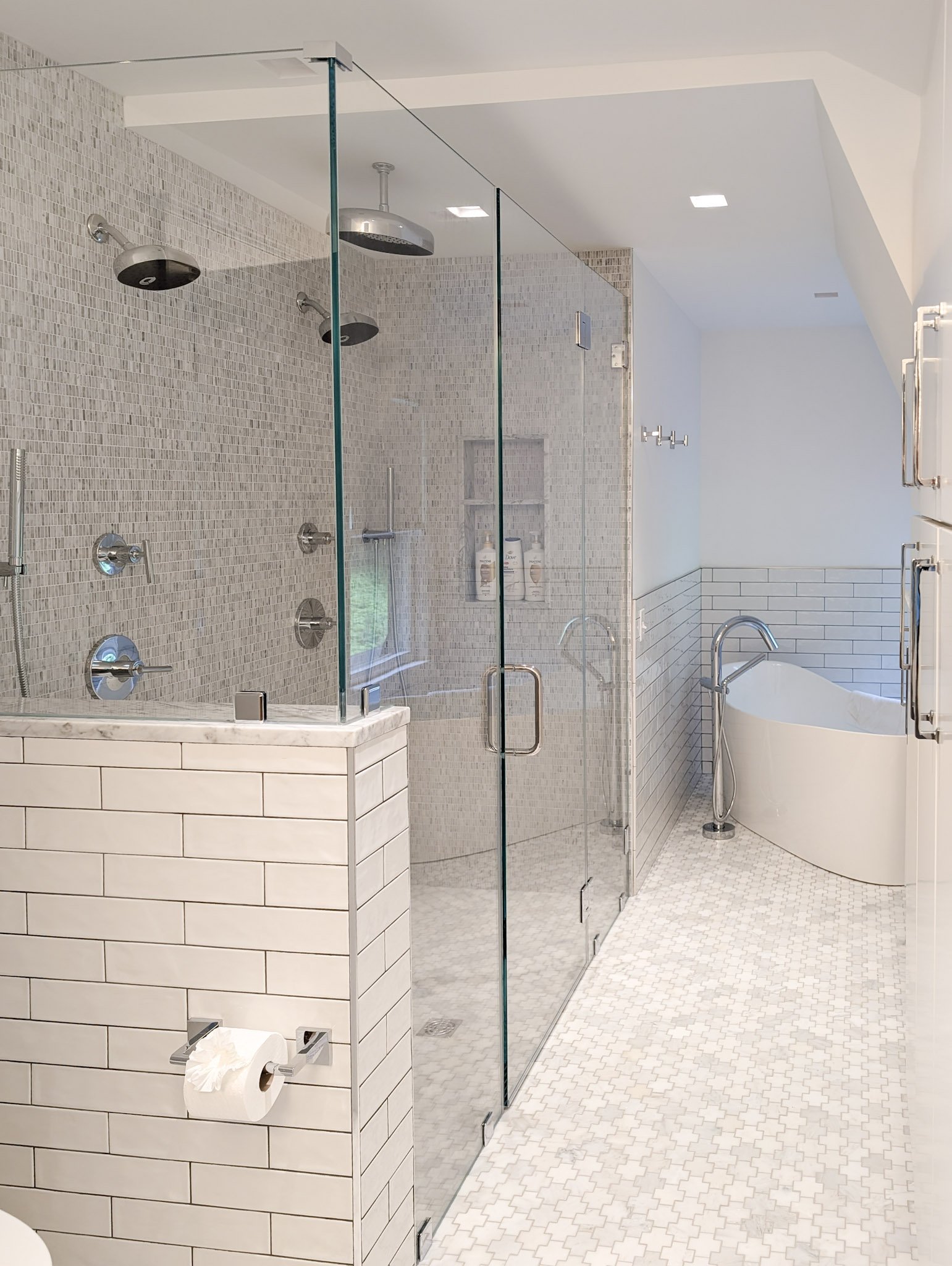 view of glass door shower tile walls and floors. a soaking tub in the background