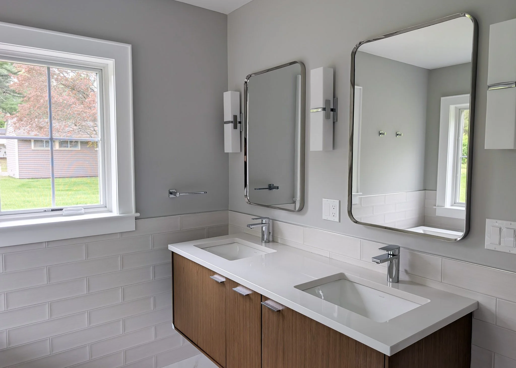 Bathroom vanity with two sinks. Two rounded corner mirrors on the walls above sinks