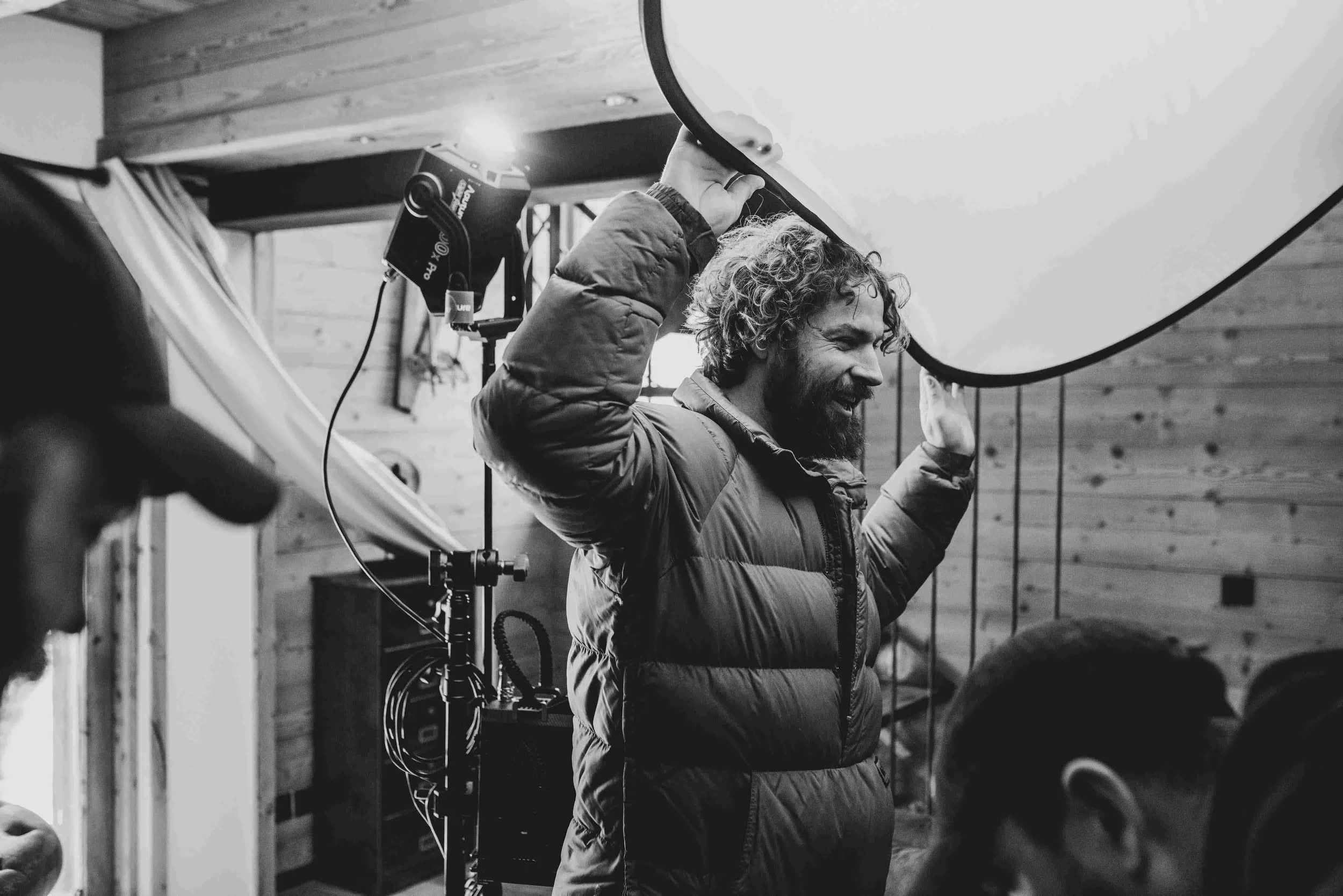 Film crew assistant holding up a diffuser on set