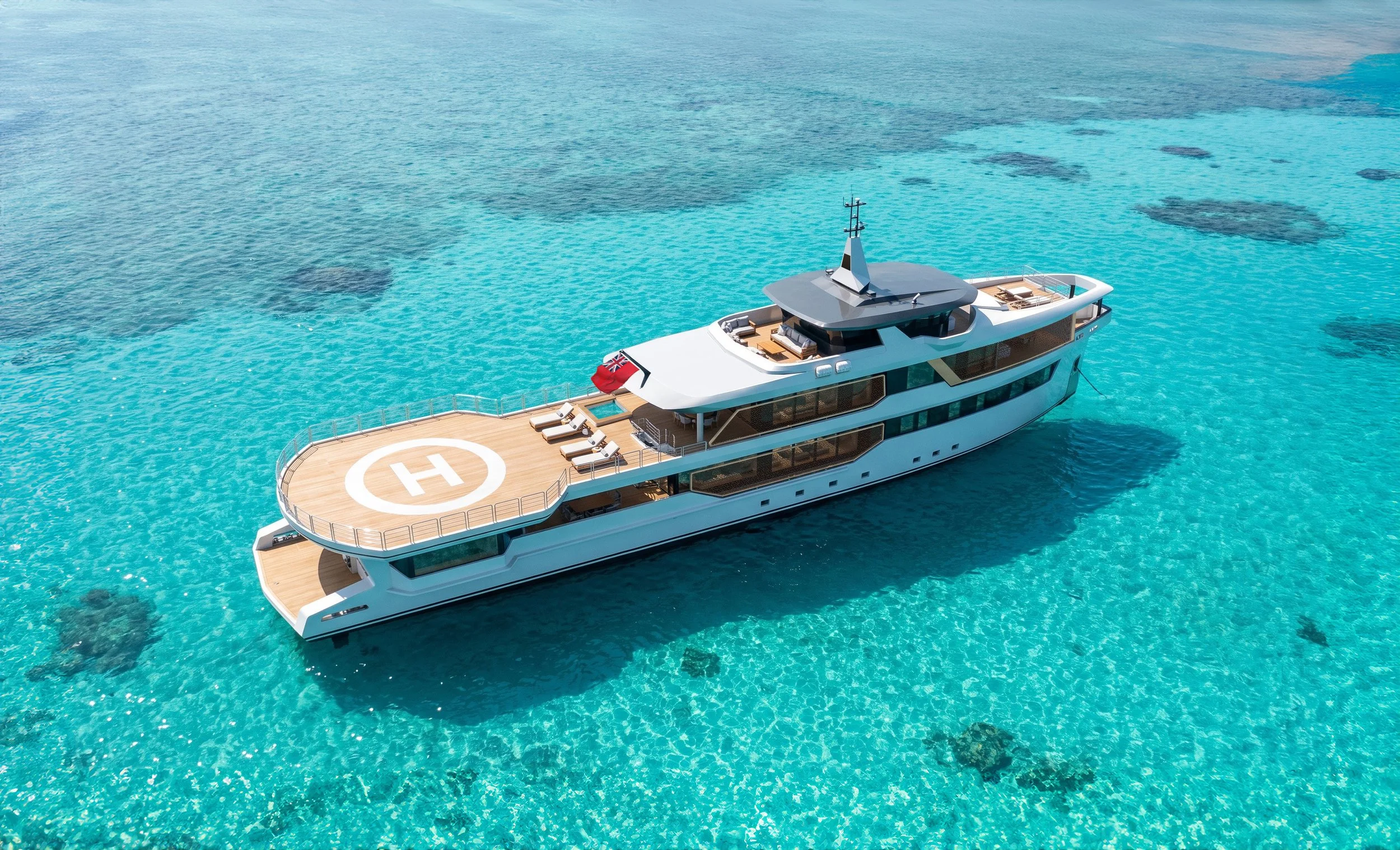 A luxury yacht floating on clear blue ocean water with visible coral reefs beneath the surface.