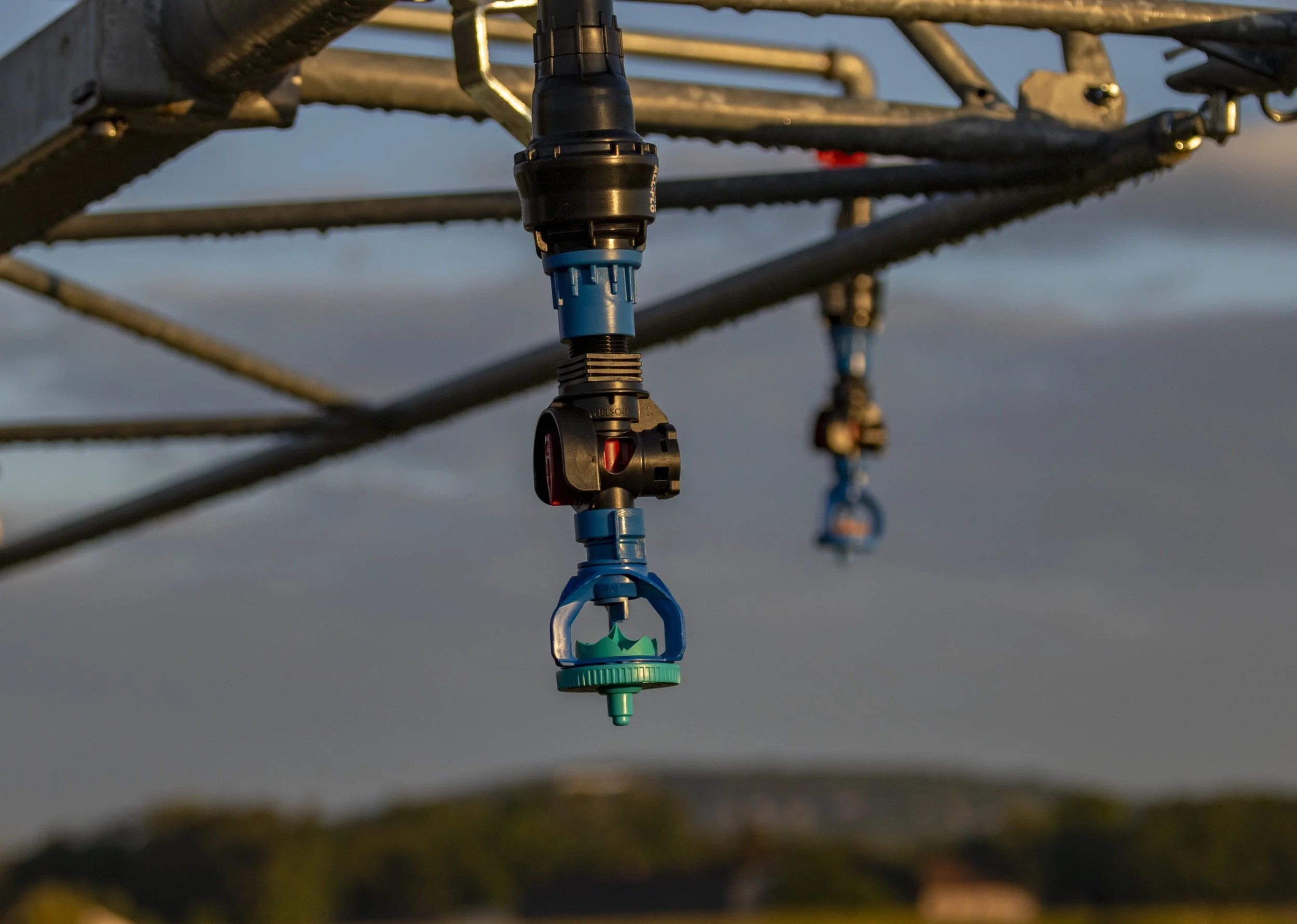 Close-up of irrigation nozzles attached to metal pipes under a clear sky.