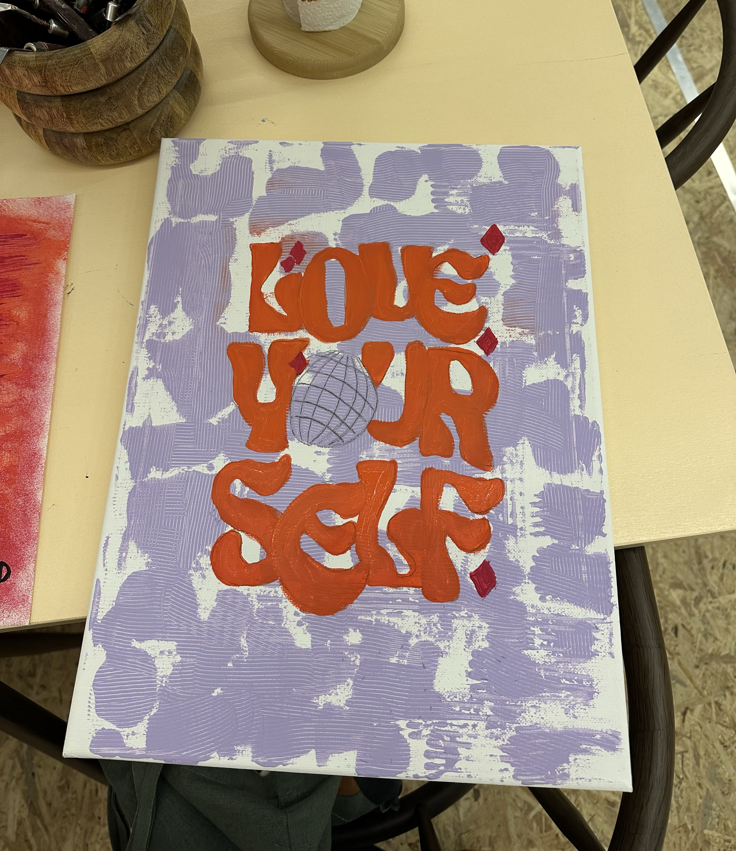 Künstlerin mischt grüne Farbe auf einer bunten Palette, die mit verschiedenen Farben wie Rot, Gelb, Blau gemischt ist.