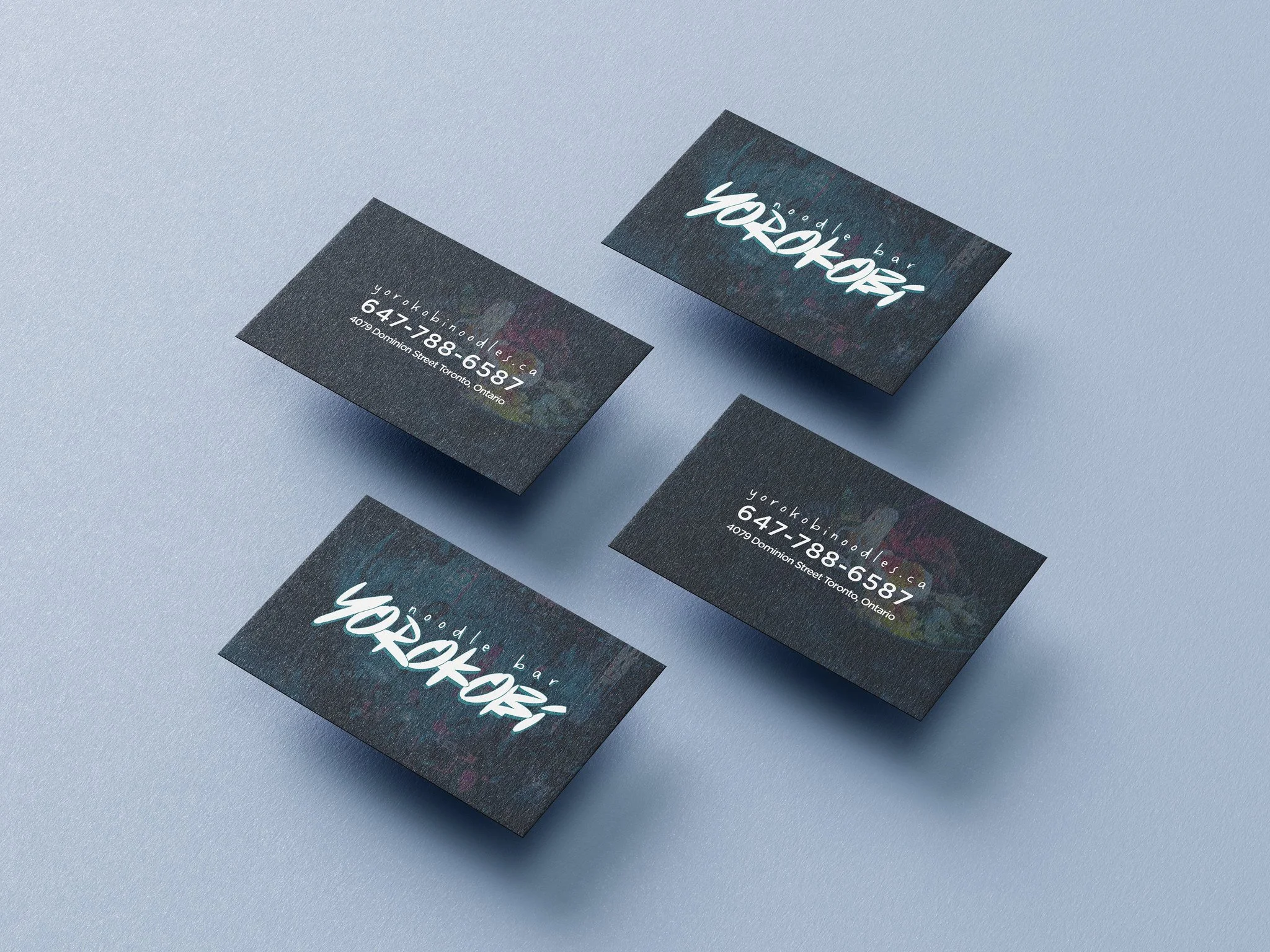 Business cards with a dark textured background, featuring the name 'yorokobi' in a white, stylized script font and thin white text displaying contact information.