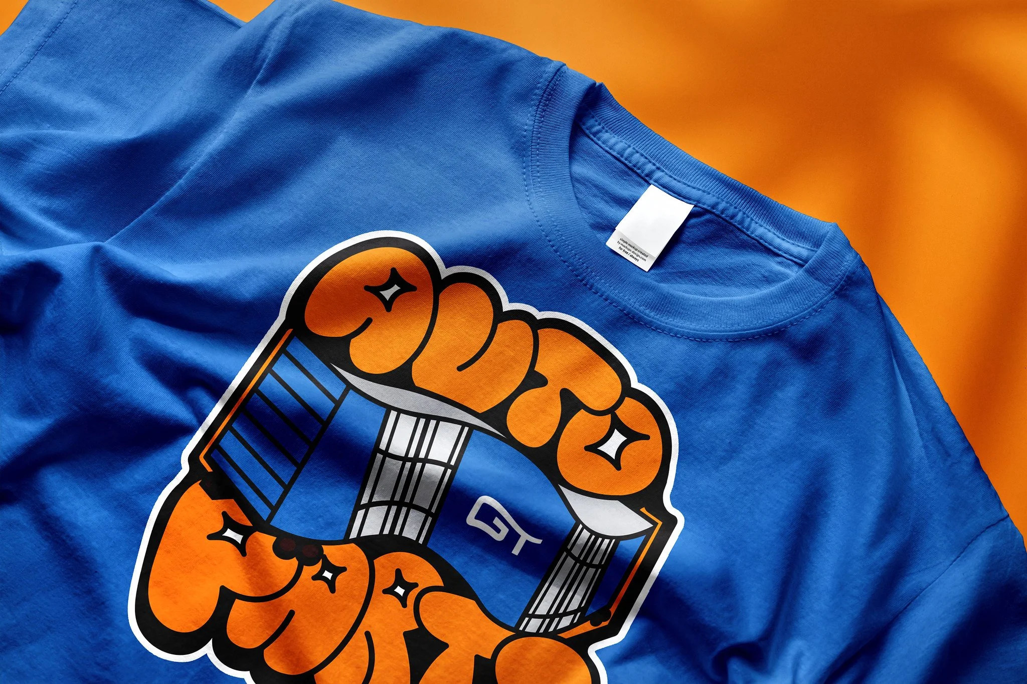 Blue T-shirt with a graphic design of a raised fist gripping a staff with the letters 'GT' on it, on an orange background.