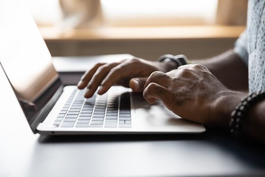 Person typing on a laptop keyboard in a home or office setting.