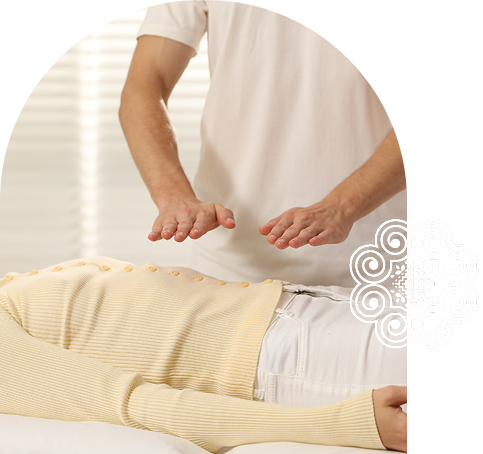 Practitioner performing Reiki healing on a person lying face down on a massage table