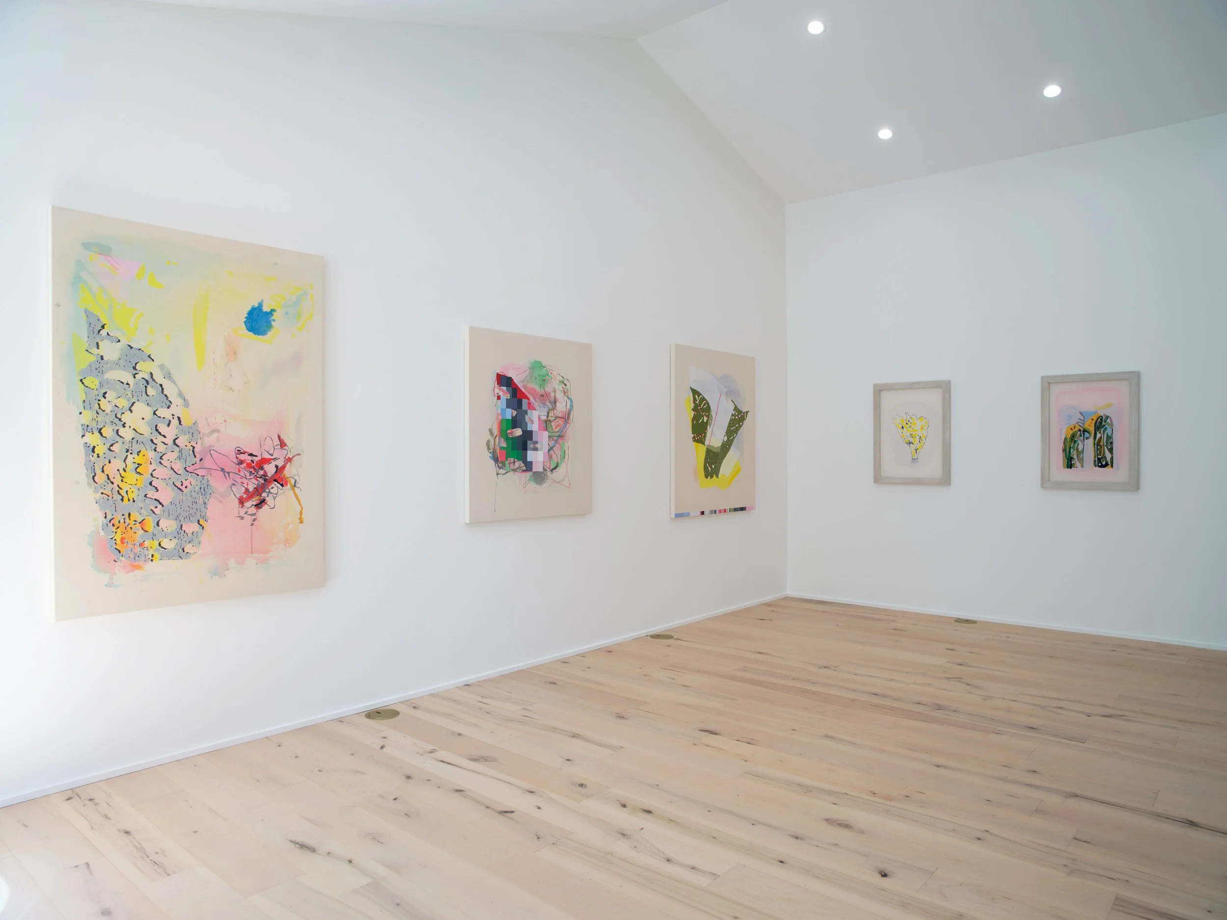 Interior view of an art gallery with white walls displaying colorful abstract paintings. Light wood flooring and ceiling with recessed lighting.