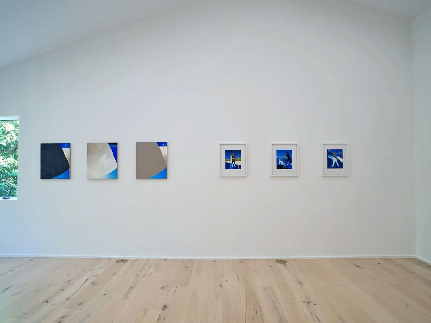 An art gallery with six framed artworks on a white wall. The first three are abstract paintings with geometric shapes in shades of blue, gray, and beige. The next three are photographs of a person walking a dog, each with a blue background, framed in white.