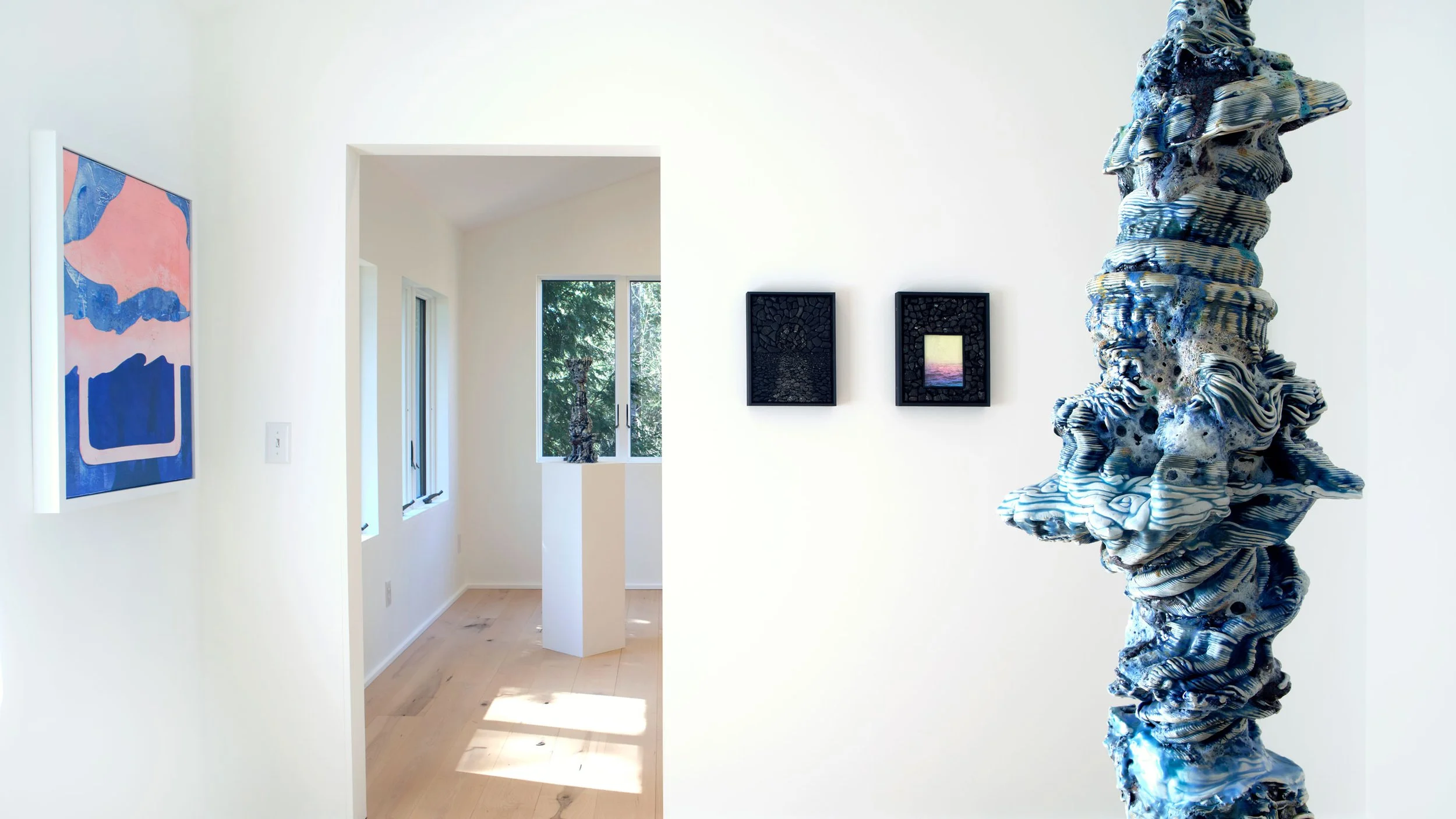 Art gallery with a large abstract sculpture shaped like a twisted, layered figure, and framed artworks on the white walls