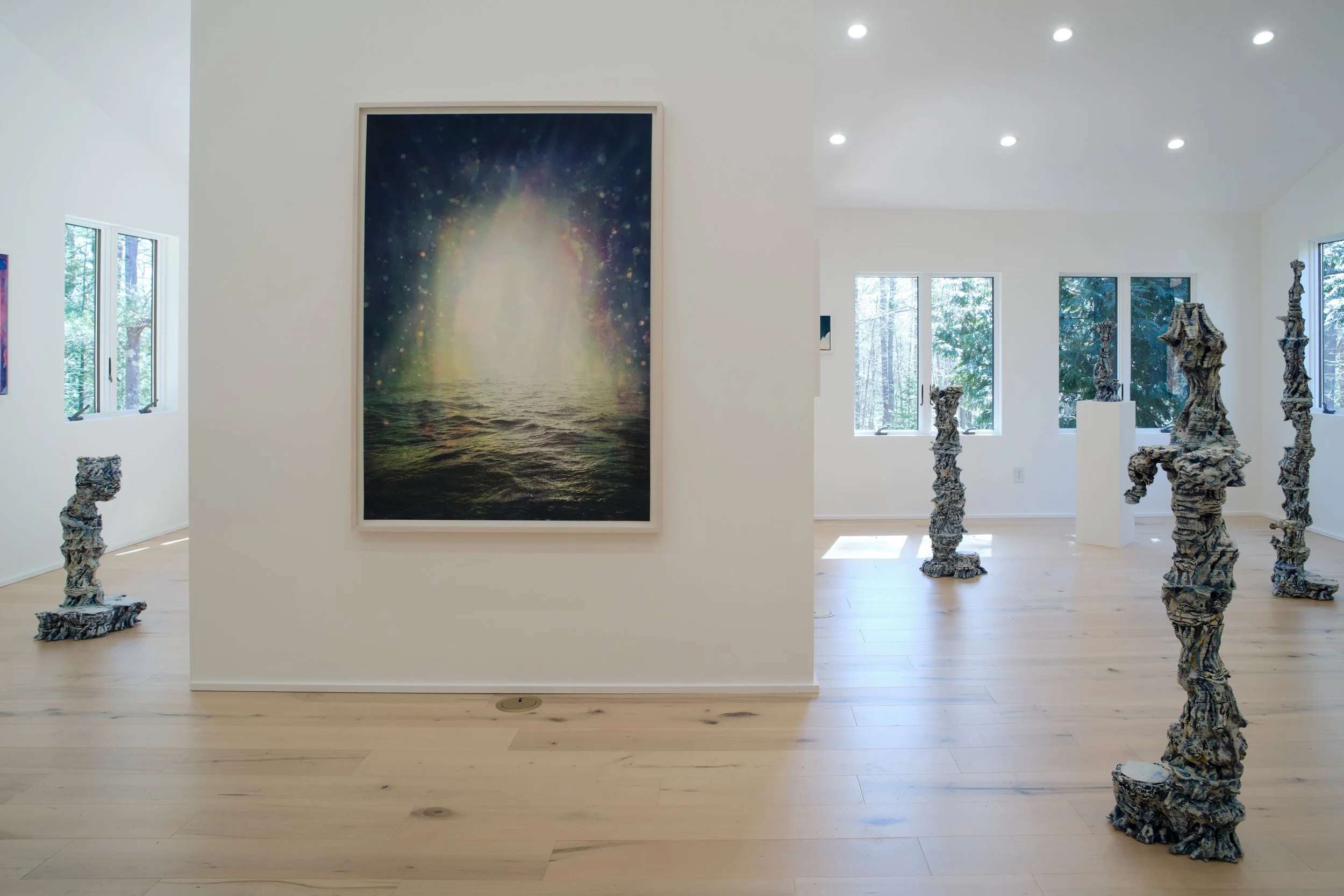 Art gallery with a framed cosmic scene painting and abstract sculptures resembling driftwood or natural formations.