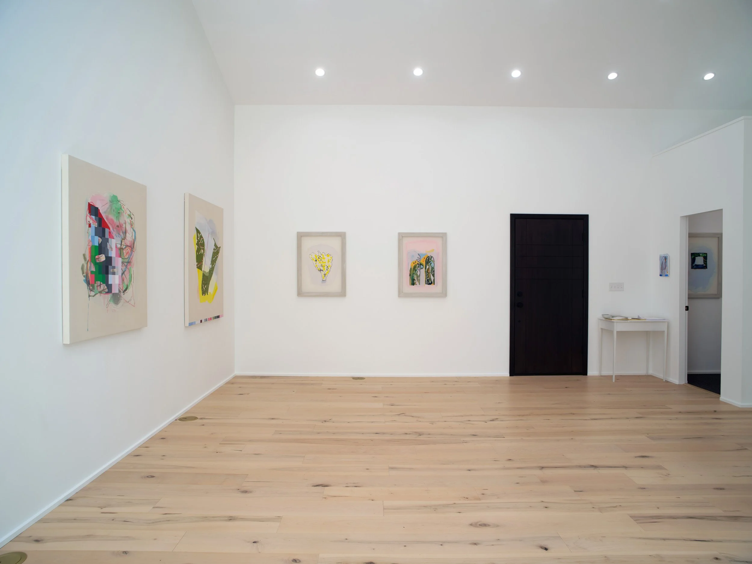 A modern art gallery with white walls, wooden floors, and various colorful artworks hanging on the wall.