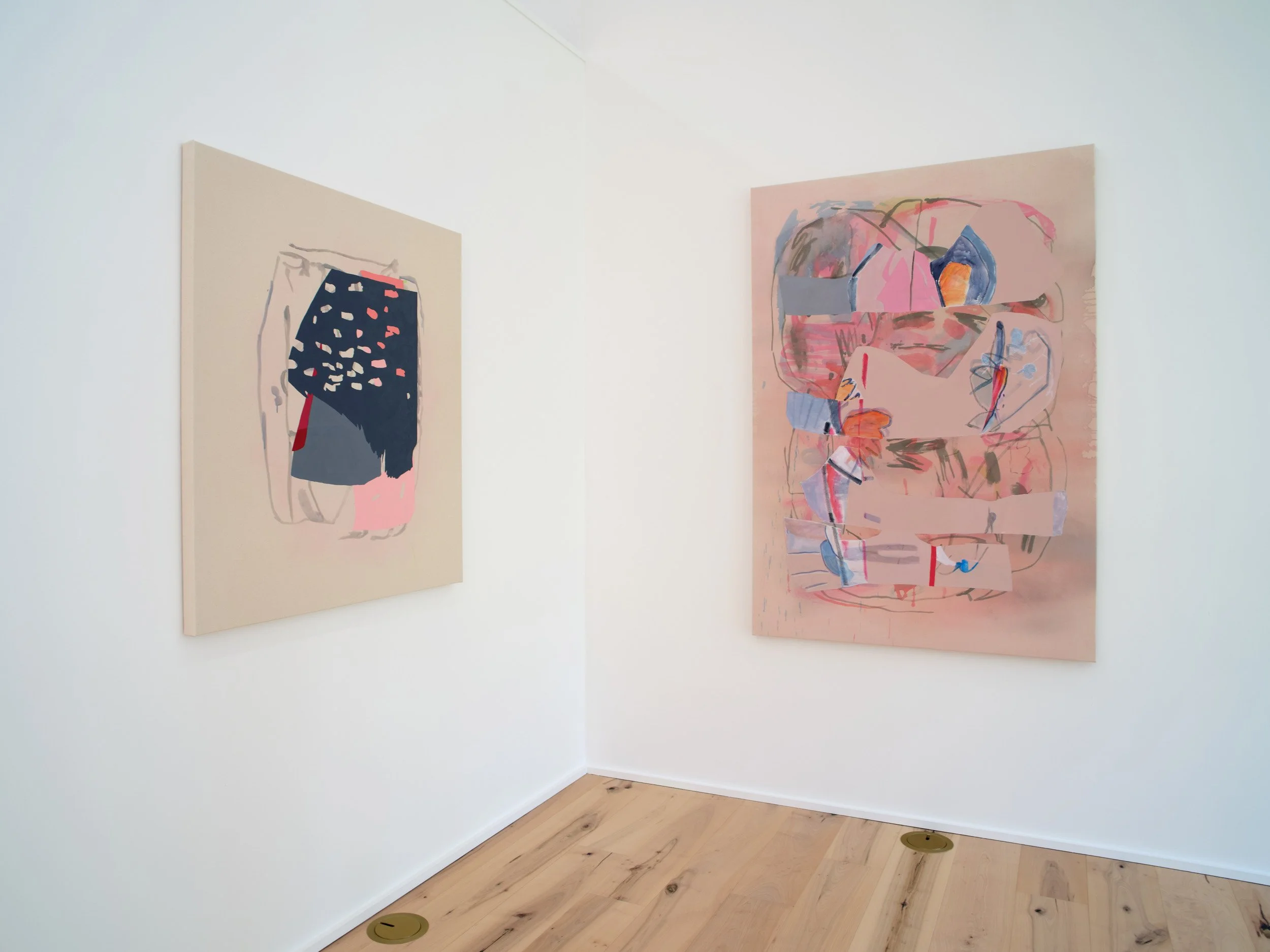 Two abstract expressionist paintings hung on white gallery walls, one with dark and pink splashes, the other with pink and blue strokes. The gallery corner has light wooden floors.