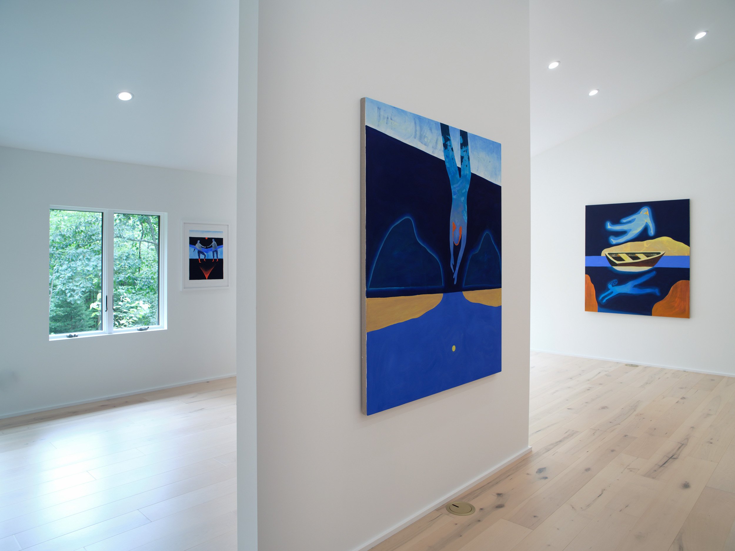 View of an art gallery with white walls, showing three paintings, and a window revealing green trees outside.