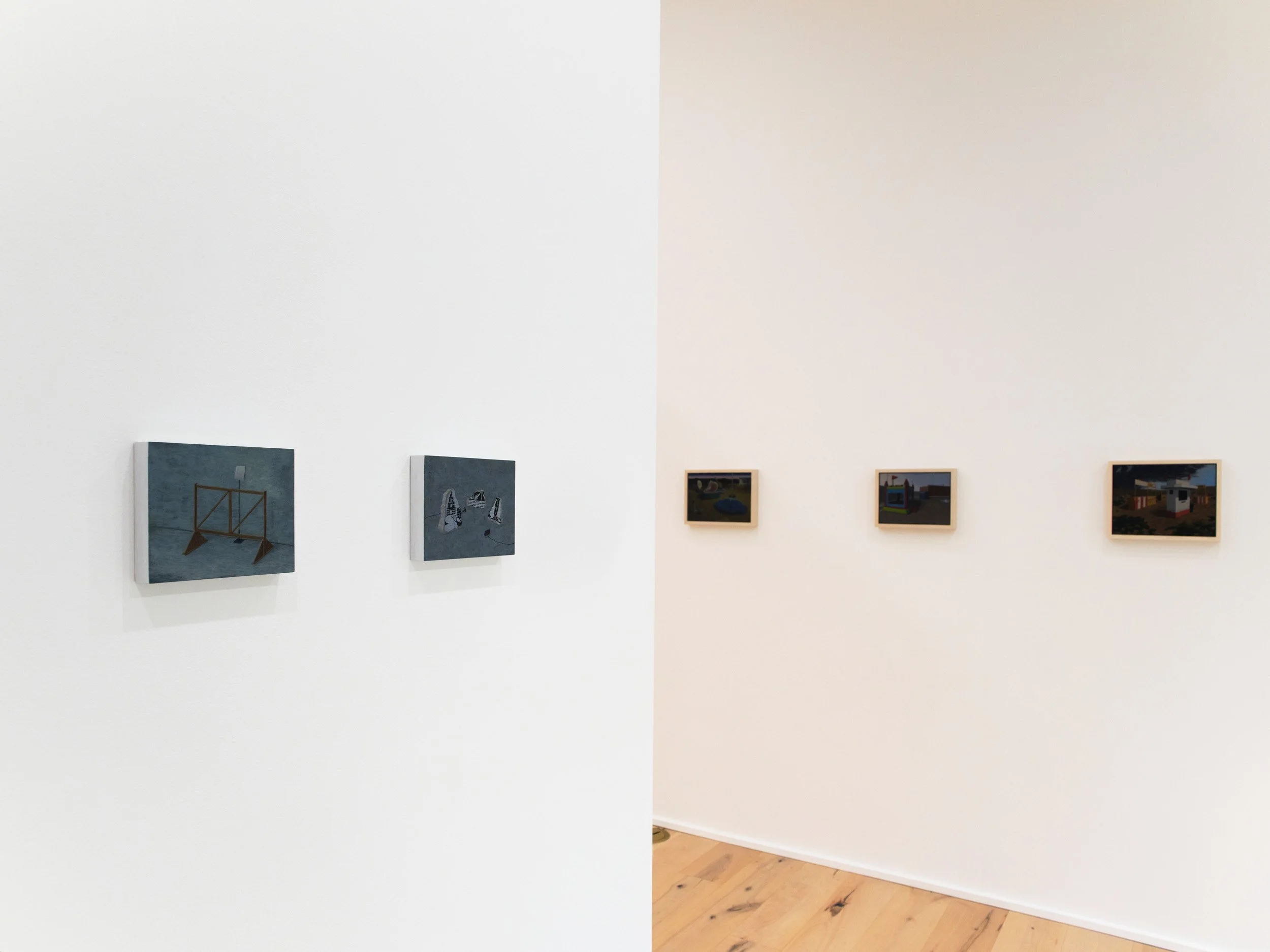 Art gallery with small framed paintings on white walls, part of the artworks are visible.