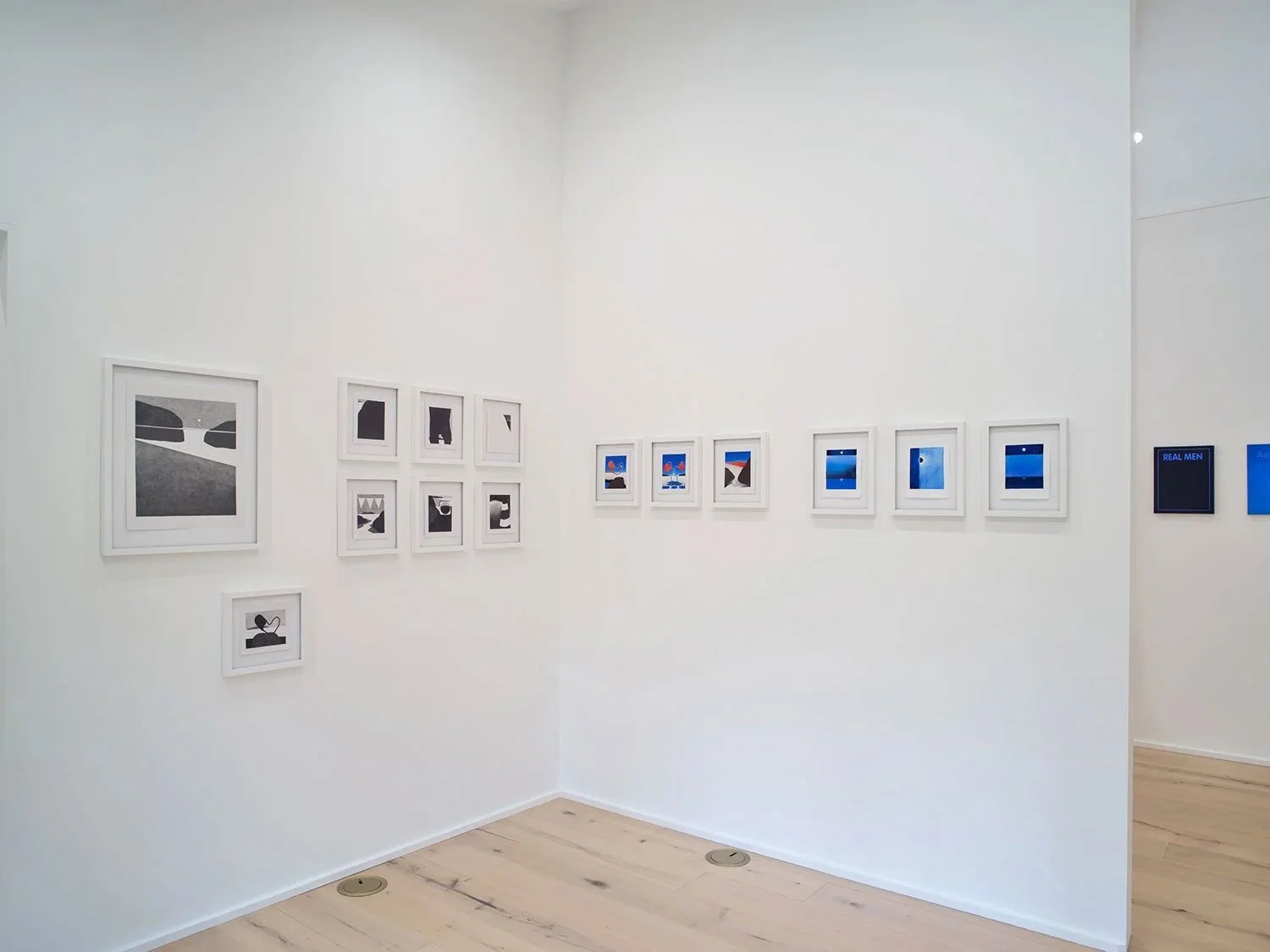 Art gallery with framed abstract and landscape artworks on white walls, light wooden flooring.