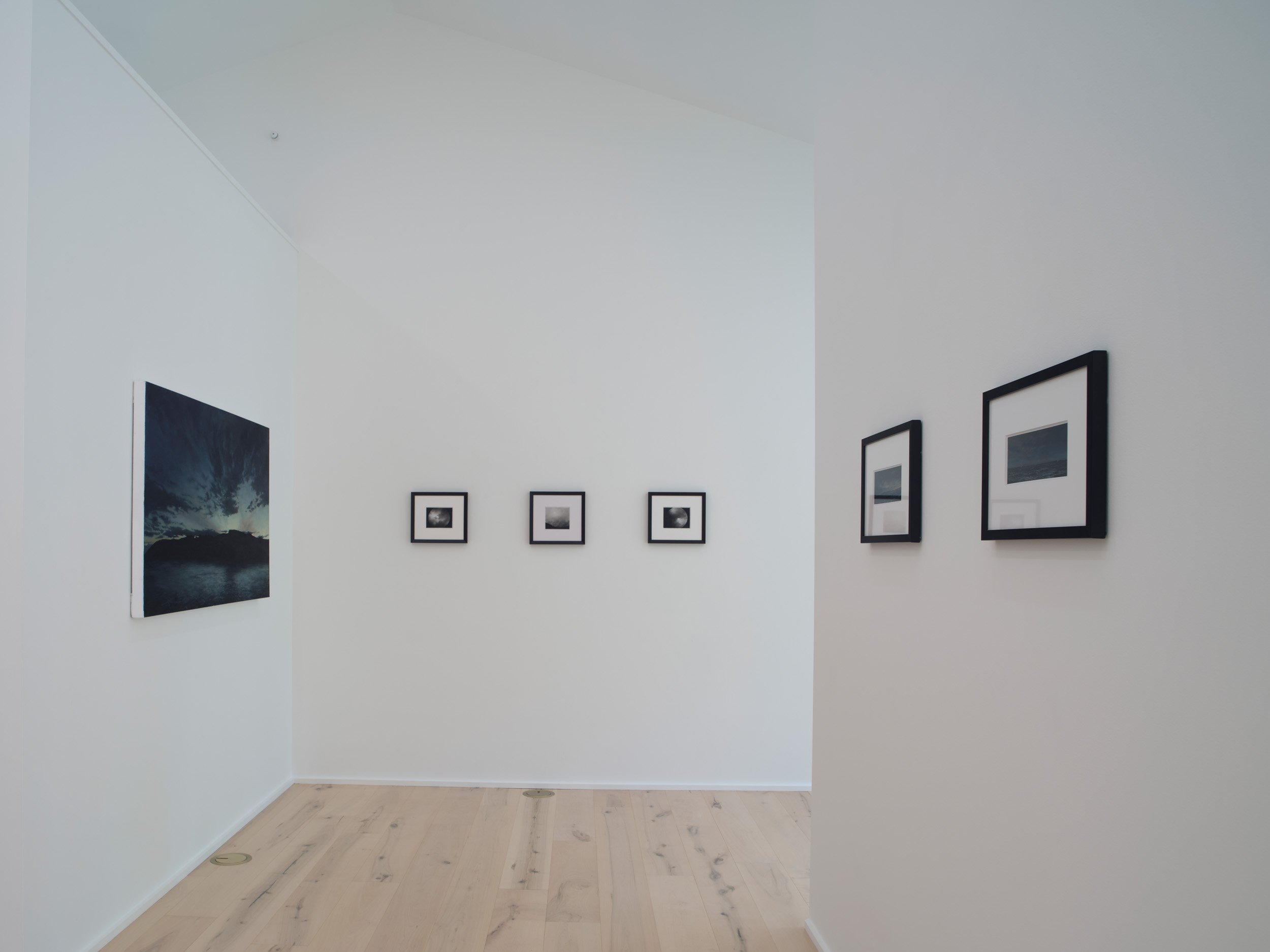 Gallery wall with framed black and white photographs on a white wall in an art gallery.