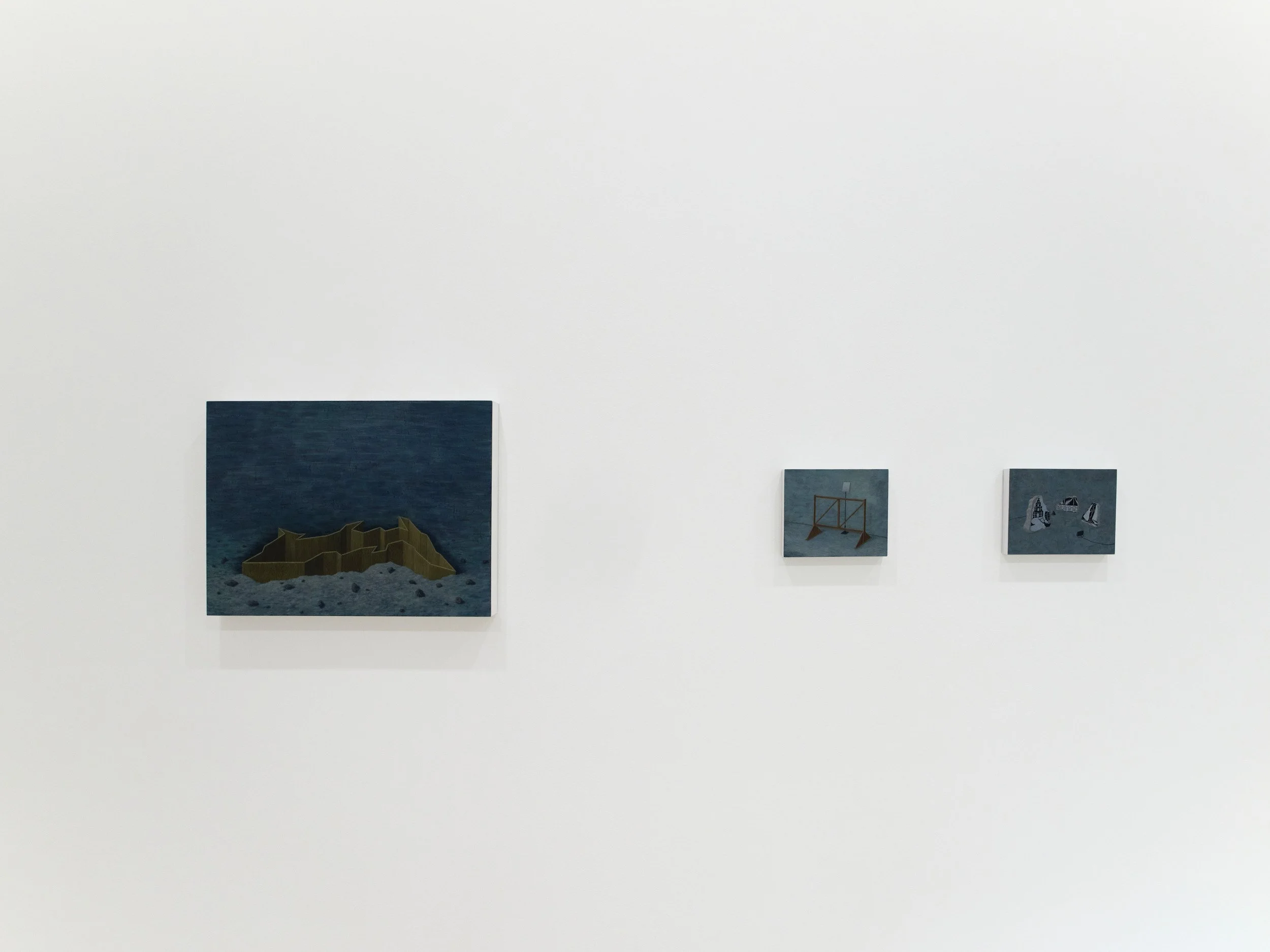 Minimalist art gallery display with four small rectangular artworks on a stark white wall.