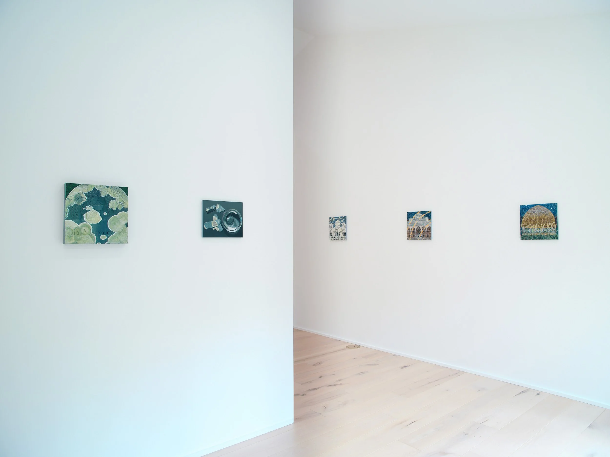 Gallery wall with artistic paintings in an art gallery with white walls and light wooden flooring.