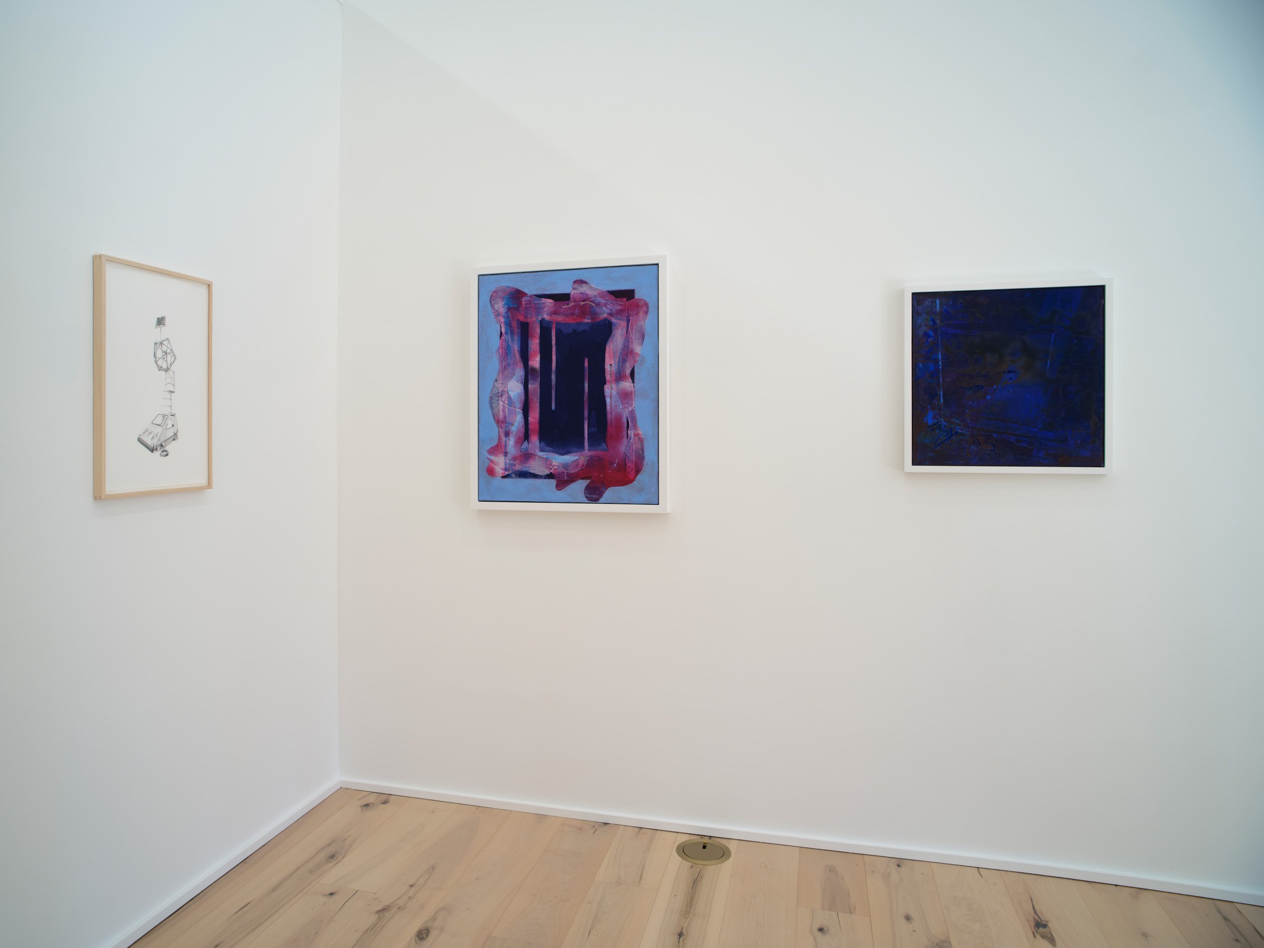 Gallery wall with three framed abstract artworks in white frames. The artworks feature abstract designs with varied colors, such as pinks, blues, and dark shades, on white walls in a minimalist setting.