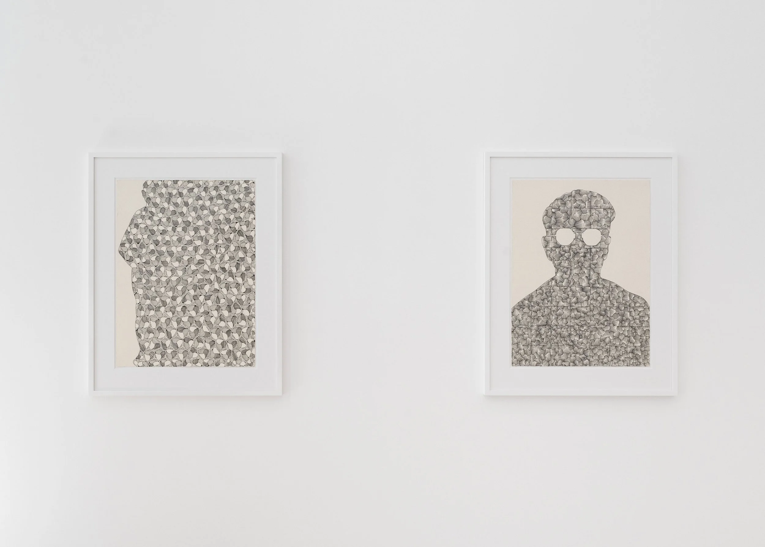 Two framed drawings on a white wall, each featuring a human head and shoulders silhouette filled with patterns of small, detailed sketches.