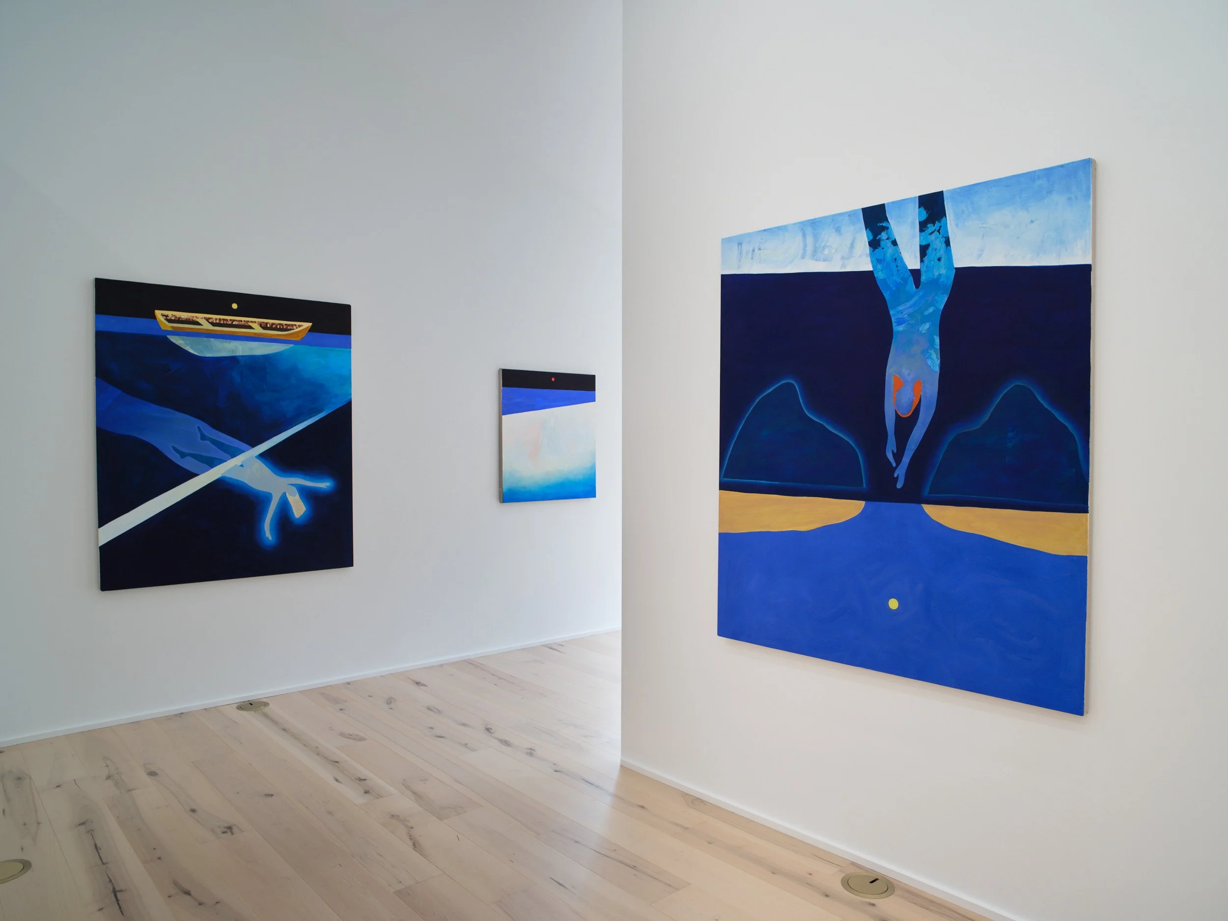 Gallery walls featuring abstract and surreal blue-toned paintings in an art gallery with light wooden floors and white walls.