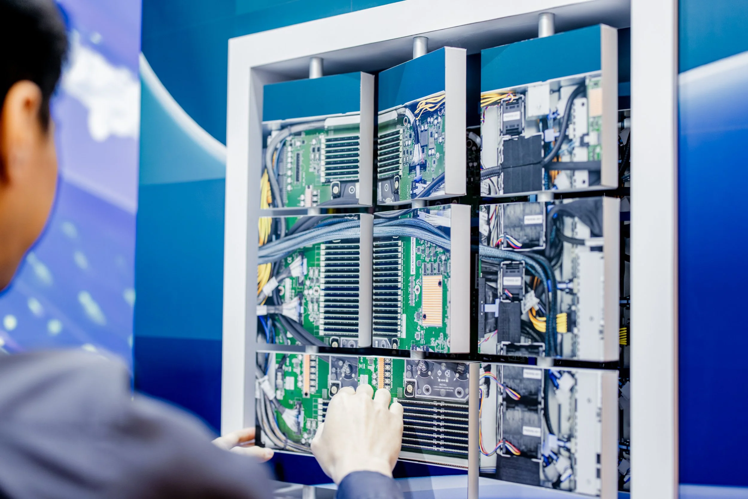 Technician working inside an open electrical or computer cabinet with circuit boards, wiring, and hardware components.