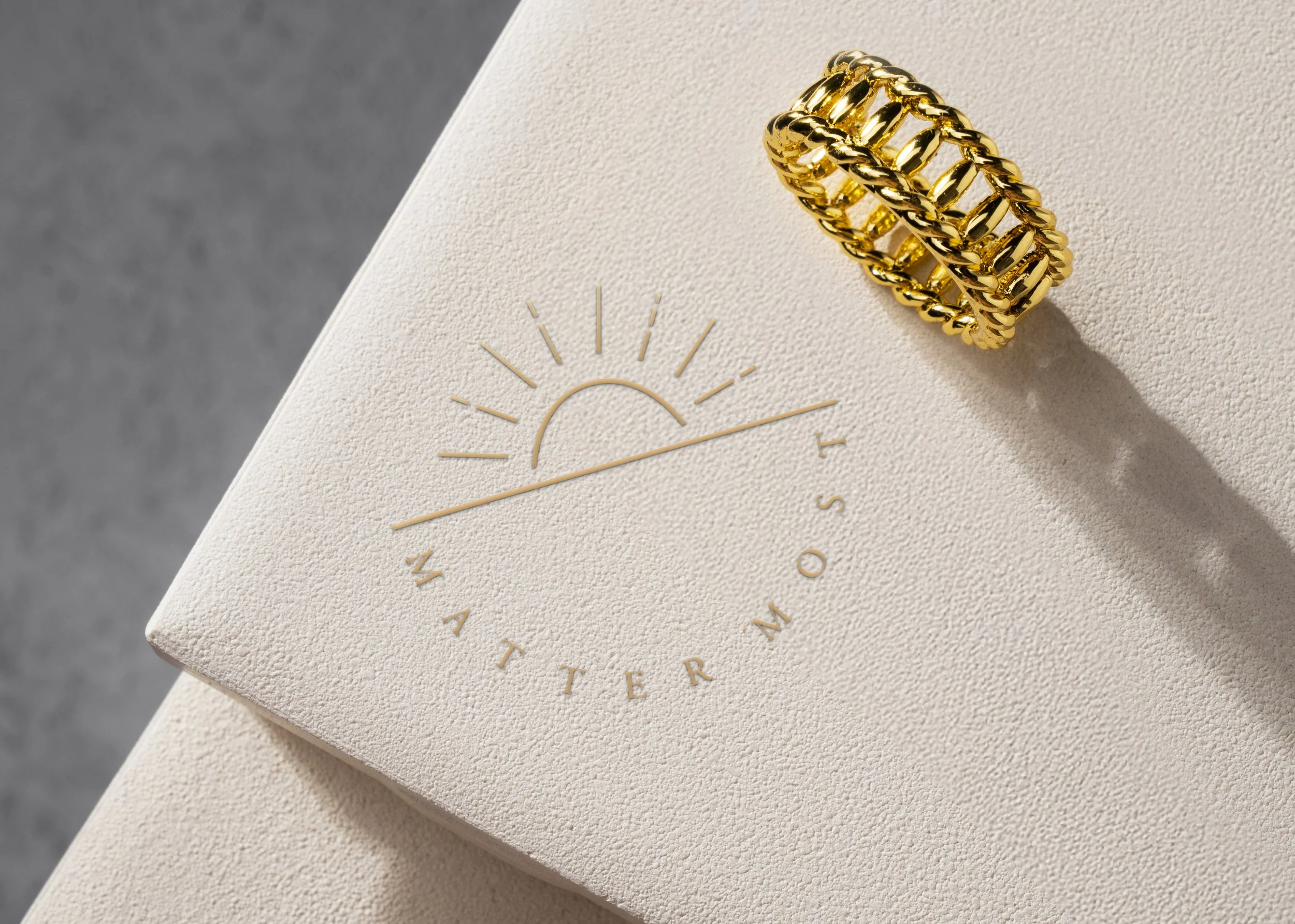 A gold chain link bracelet resting on a textured white surface with a printed clock design.