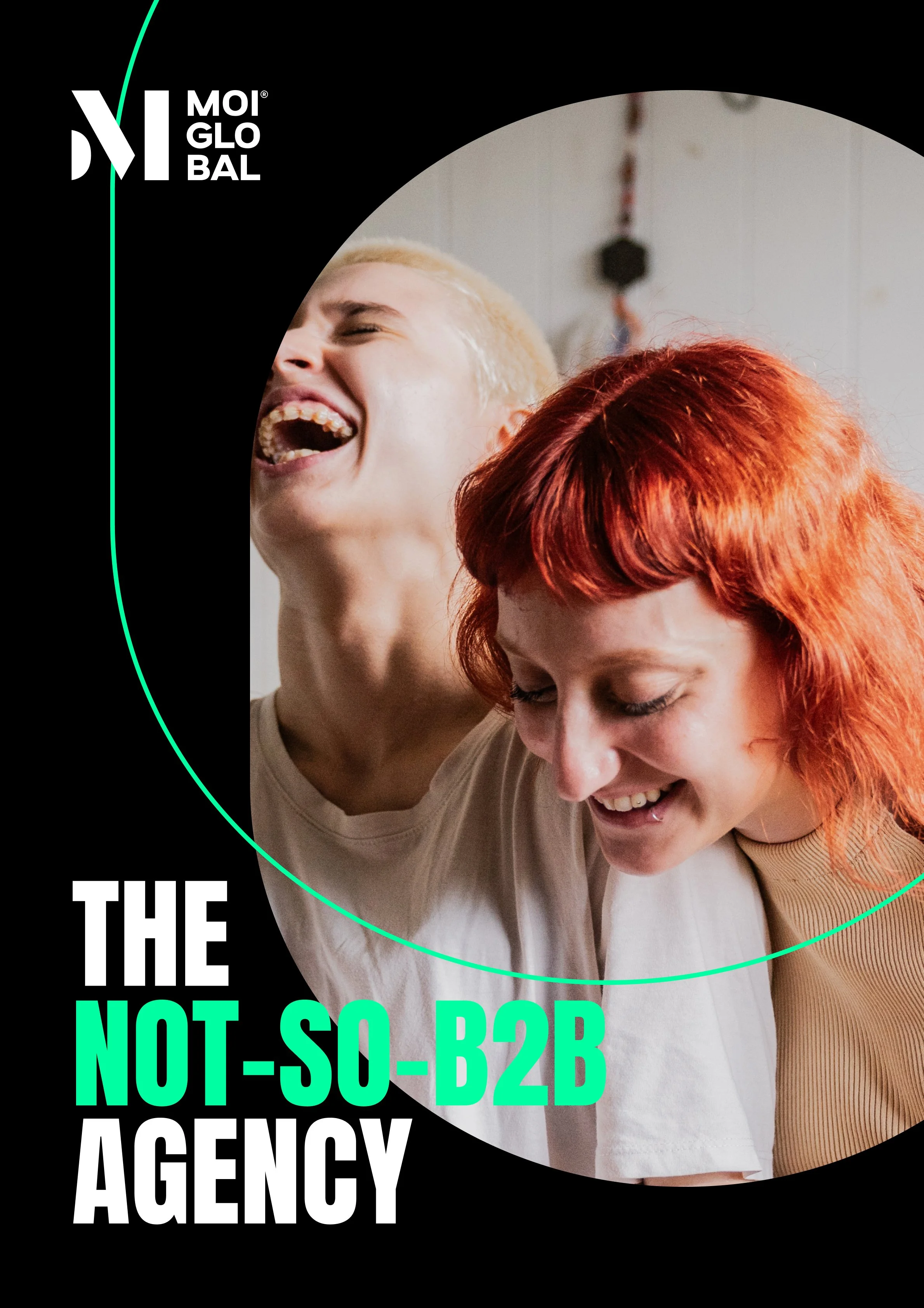 Two young women with short hair, one with blonde and the other with red hair, laughing and smiling together. They are close together, and the background shows a neutral indoor setting.