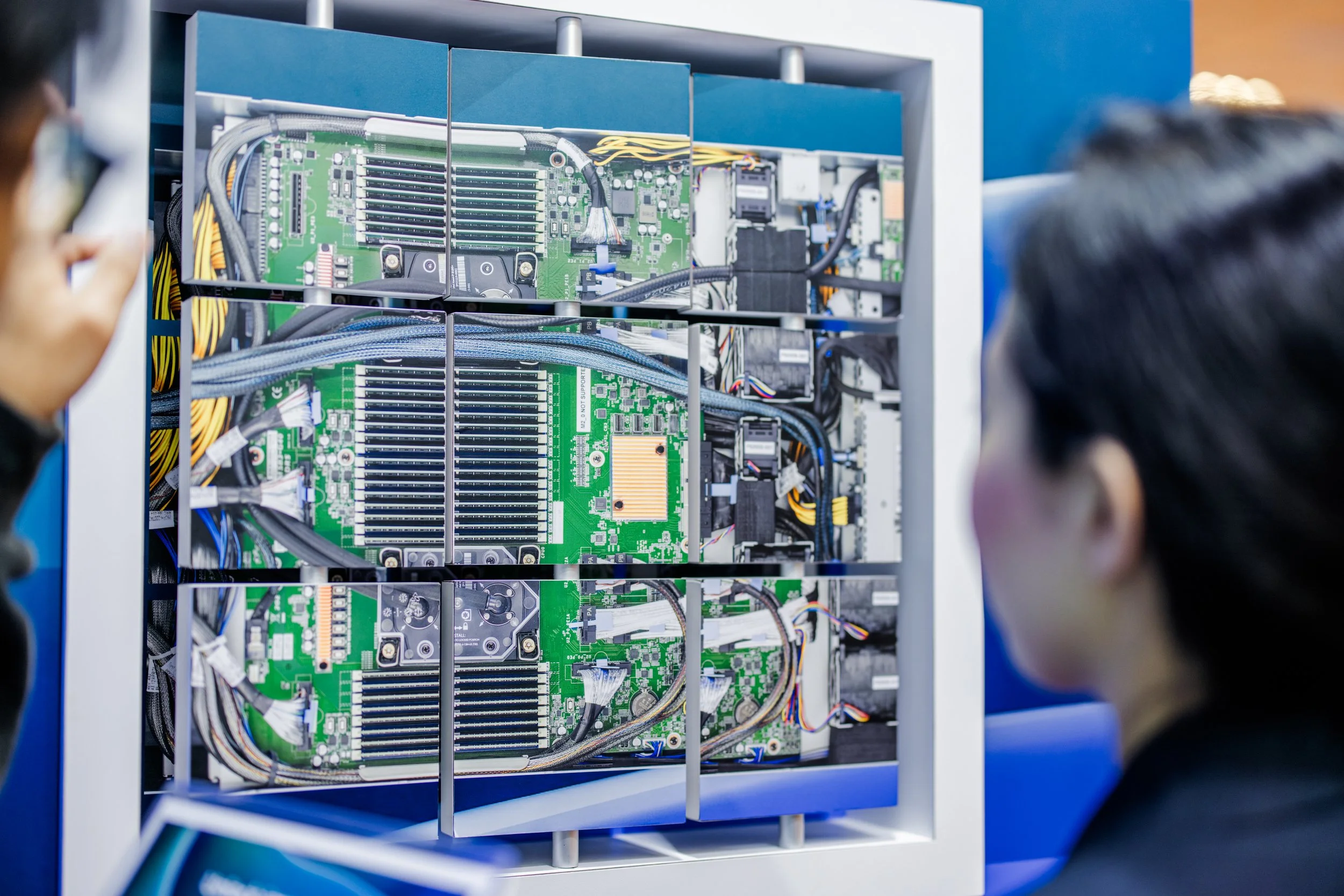 People inspecting an open computer or server with visible circuit boards and wiring.