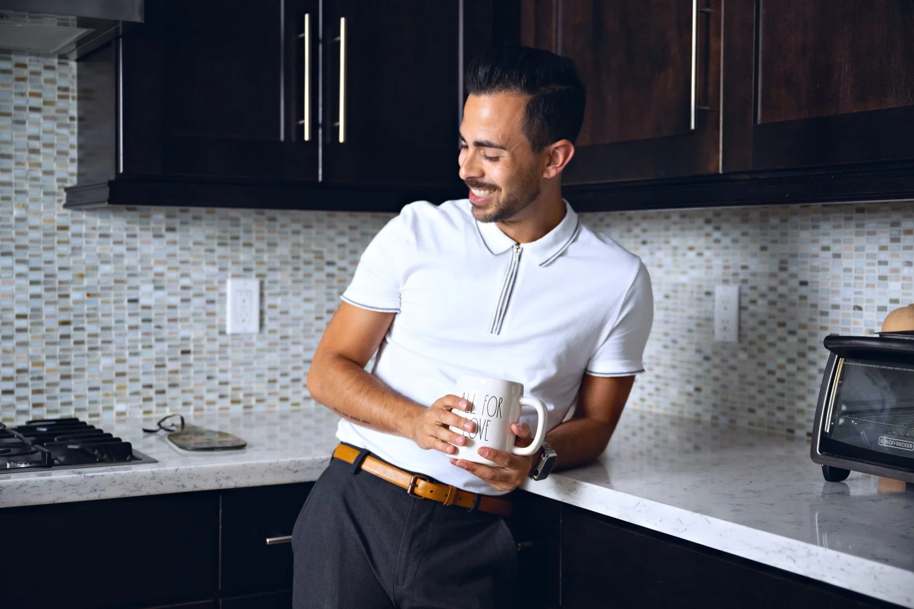 Man in kitchen holding coffee mug: Danny Morales — relationship coach for Gay and Bi men