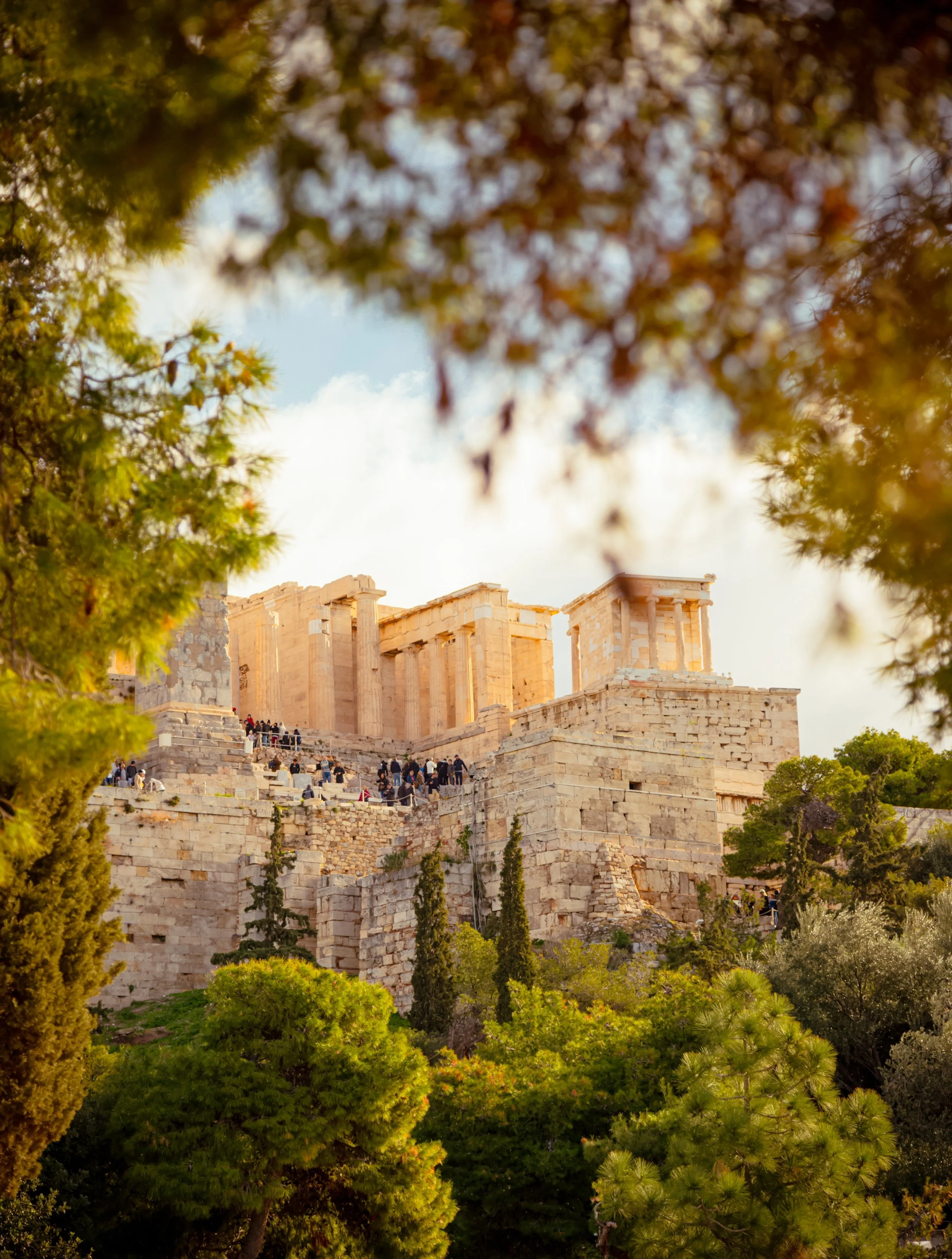Ancient Greek Parthenon temple on the Acropolis in Athens, Greece, framed by trees and foliage.