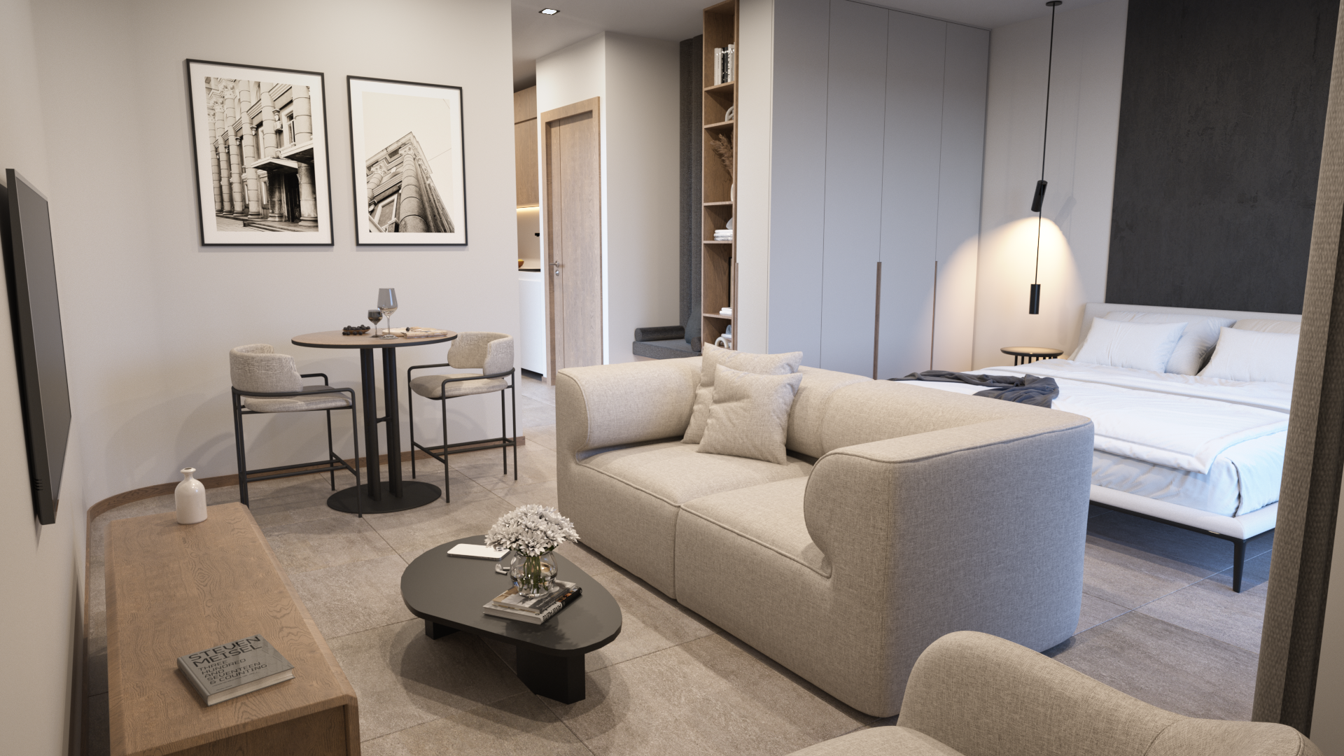 Modern hotel studio apartment with a sitting area, a bed, and minimalist decor including black and white framed architectural photos on the wall.