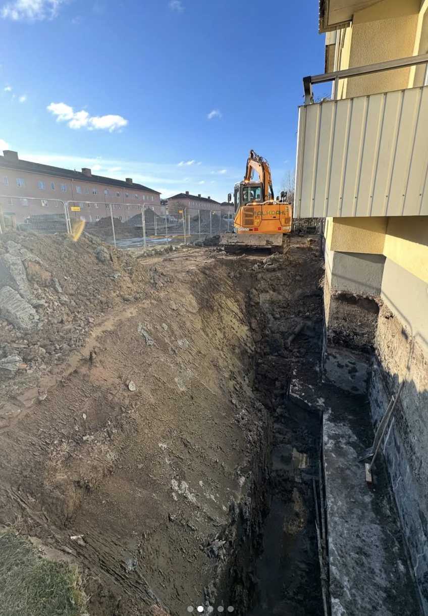 Utgrävning vid ett byggprojekt med grävmaskin och ett pågående shalm där en villa byggs.