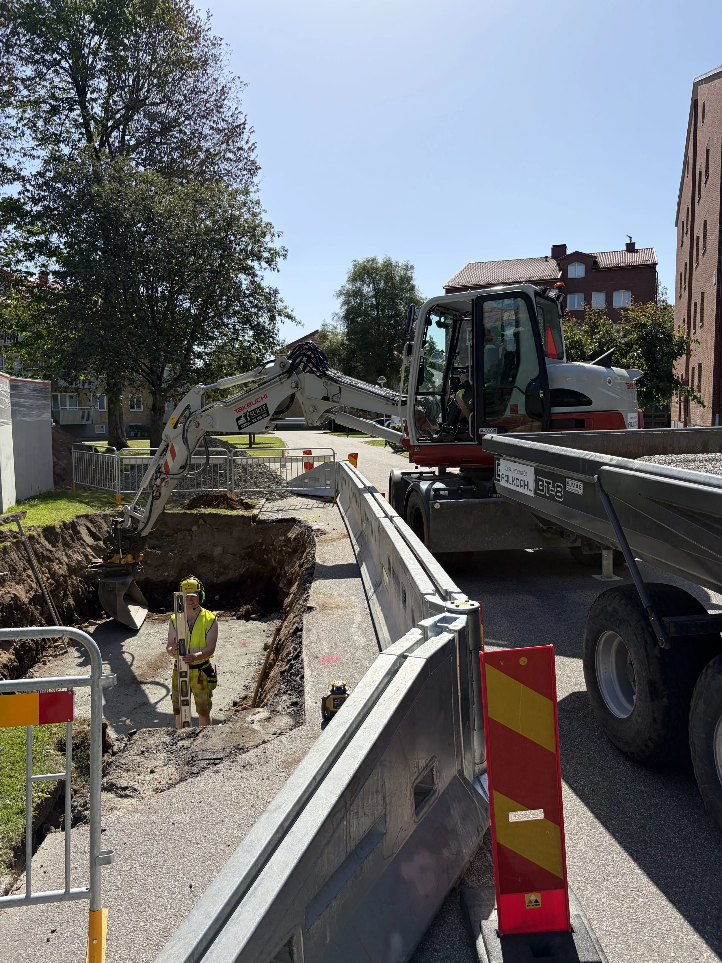 yrkesarbetare mäter och grävmaskinen syns i bakgrunden