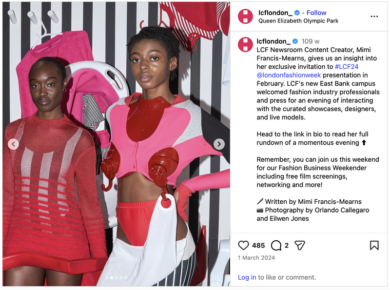 Two models at the London Fashion Week showcase with colorful clothing and accessories, standing against a backdrop with striped wall and hanging items.