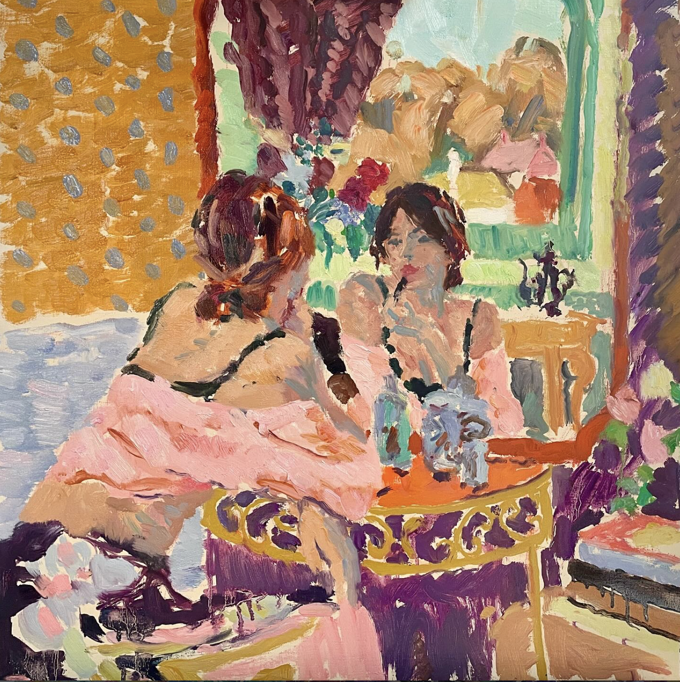 Painting of two women sitting at a table, with a colorful background including a painting, a lamp, and decor, in an impressionistic style.