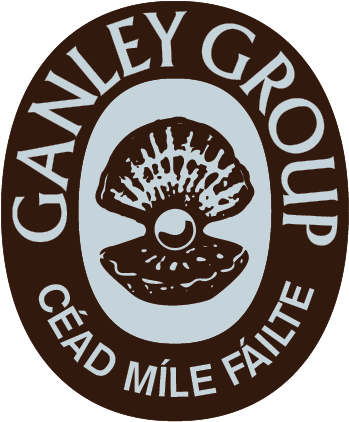 A circular logo featuring the words "GANEY GROUP" at the top and "CÉAD MÍLE FAILTE" at the bottom. In the center, there is an illustration of a clam shell opening to reveal a pearl.