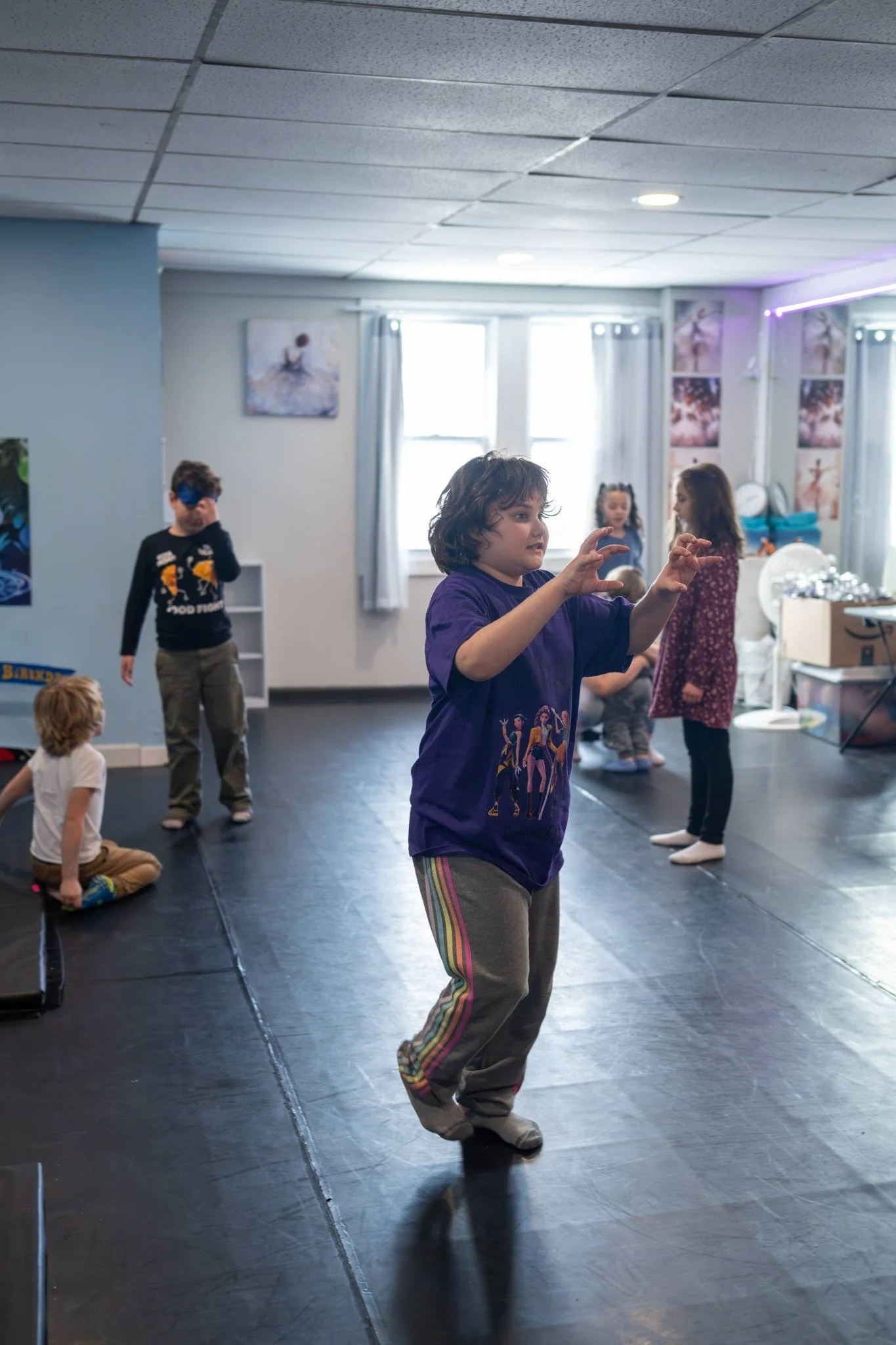 Children practicing ballet or dance in a dance studio with natural light coming through the windows.